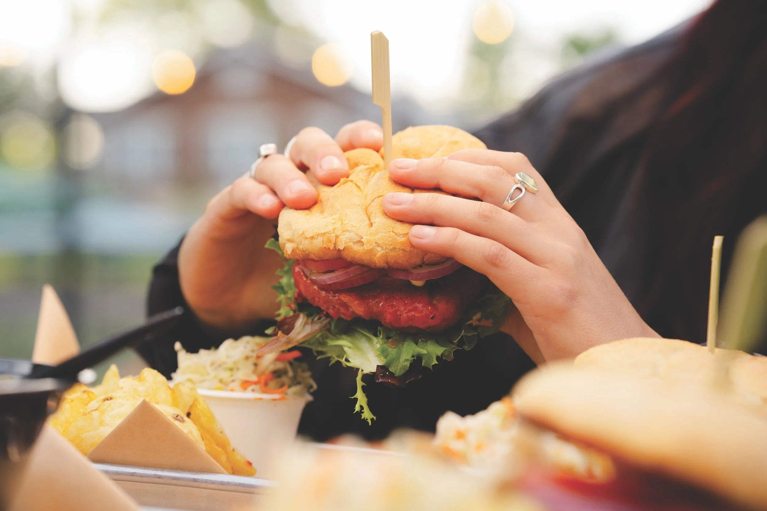 hands holding vegan burger with lettuce and tomato