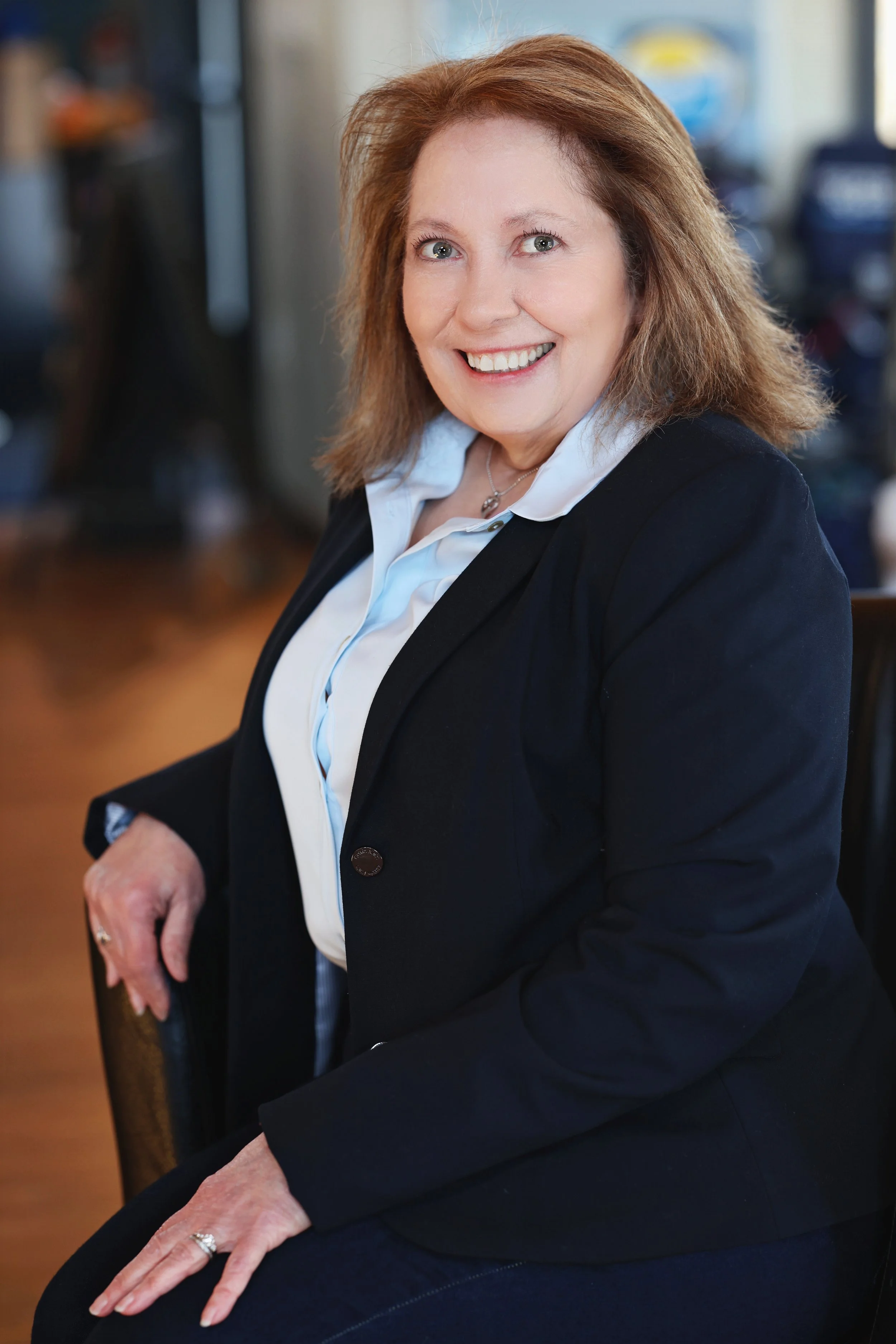 Woman with dark hair, white jacket, standing alongside a street
