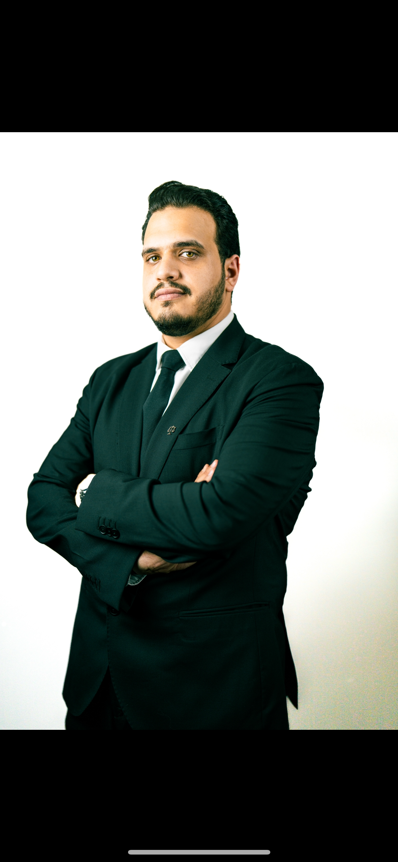 Confident man in black suit with arms crossed on white background