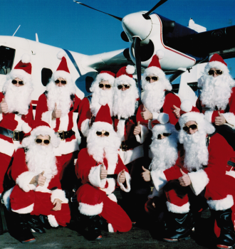 10 Flying Santas standing in front of plane