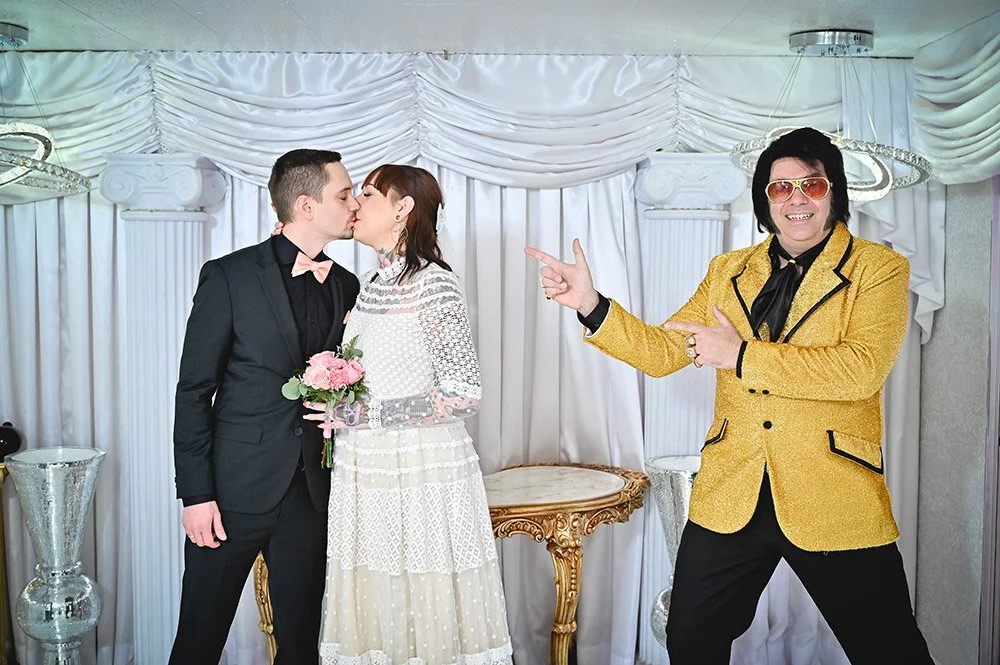 An Elvis impersonator motions to newly married couple