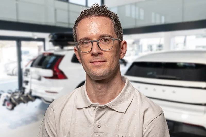 Moderne Autohändler-Rezeption mit einem weißen Schreibtisch, der das Volvo-Logo und eine Willkommensbotschaft trägt, im Hintergrund ein Service-Counter mit Computern und ein silberner Volvo XC40. 