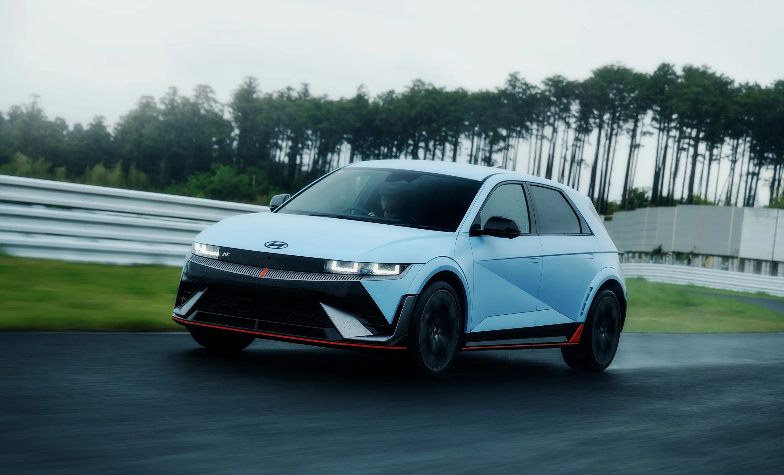 Ein blauer Hyundai Ioniq 5 fährt auf einer Rennstrecke bei nebligem Wetter.