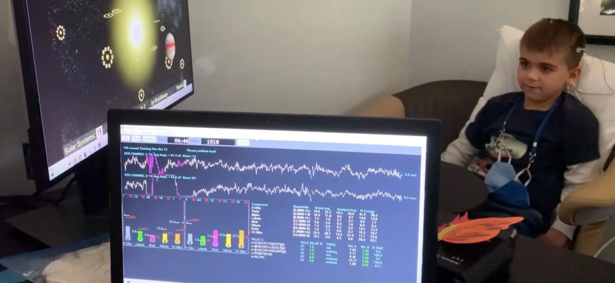 Boy during neurofeedback session with real-time brainwave data on monitors — Kerov Health custom programs