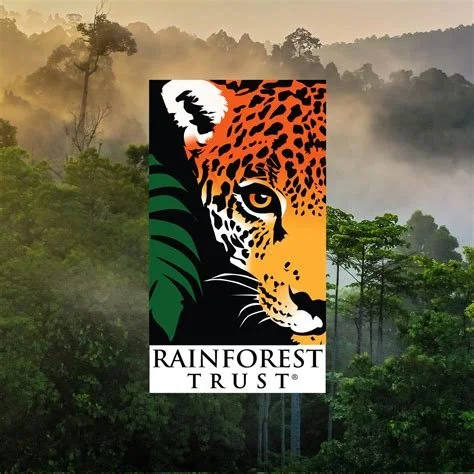 Rainforest Trust logo featuring a stylized jaguar's face with green leaves and a white moon in the background