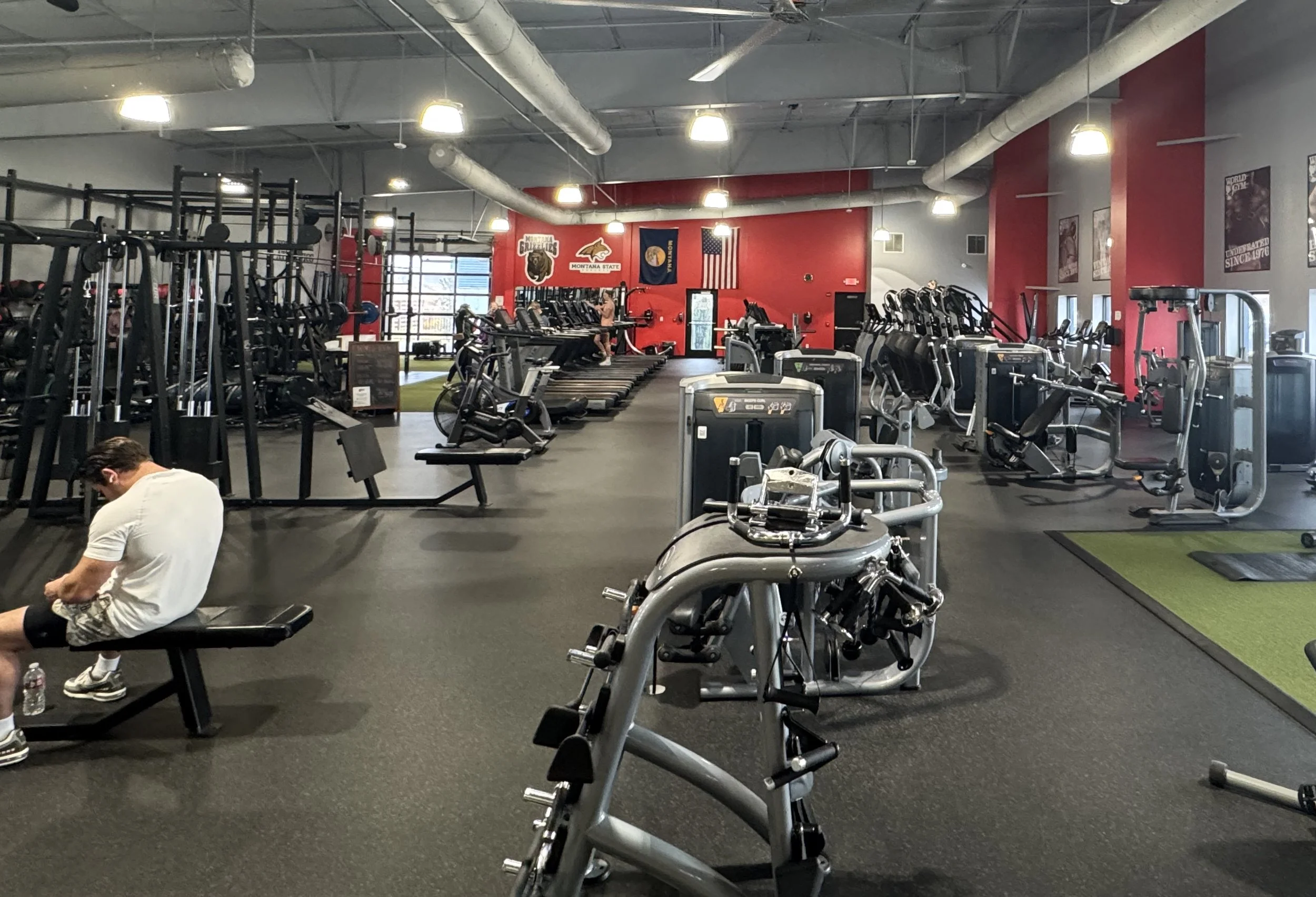East-facing view of the main fitness space with pin-machines, cardio area, and part of The Vault VIP area.