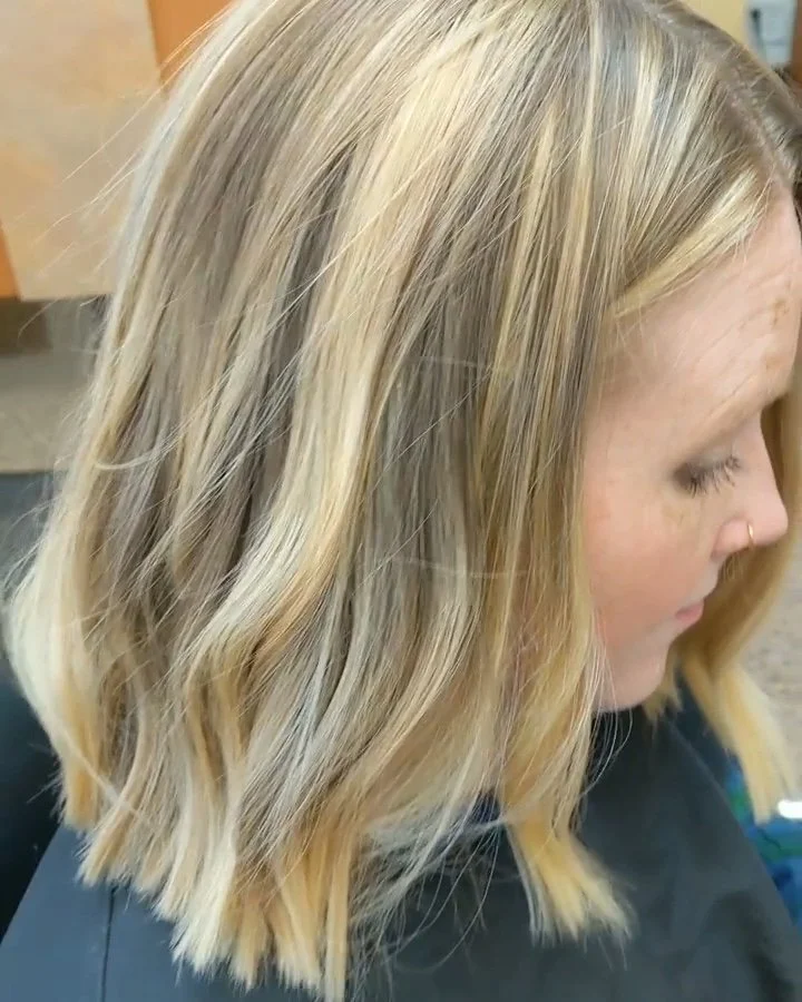 Close-up of a woman's blonde wavy hair from the side with a septum nose ring.