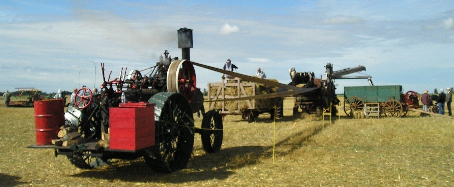 Vintage steamroller on display outdoors with a building and trees in the background.