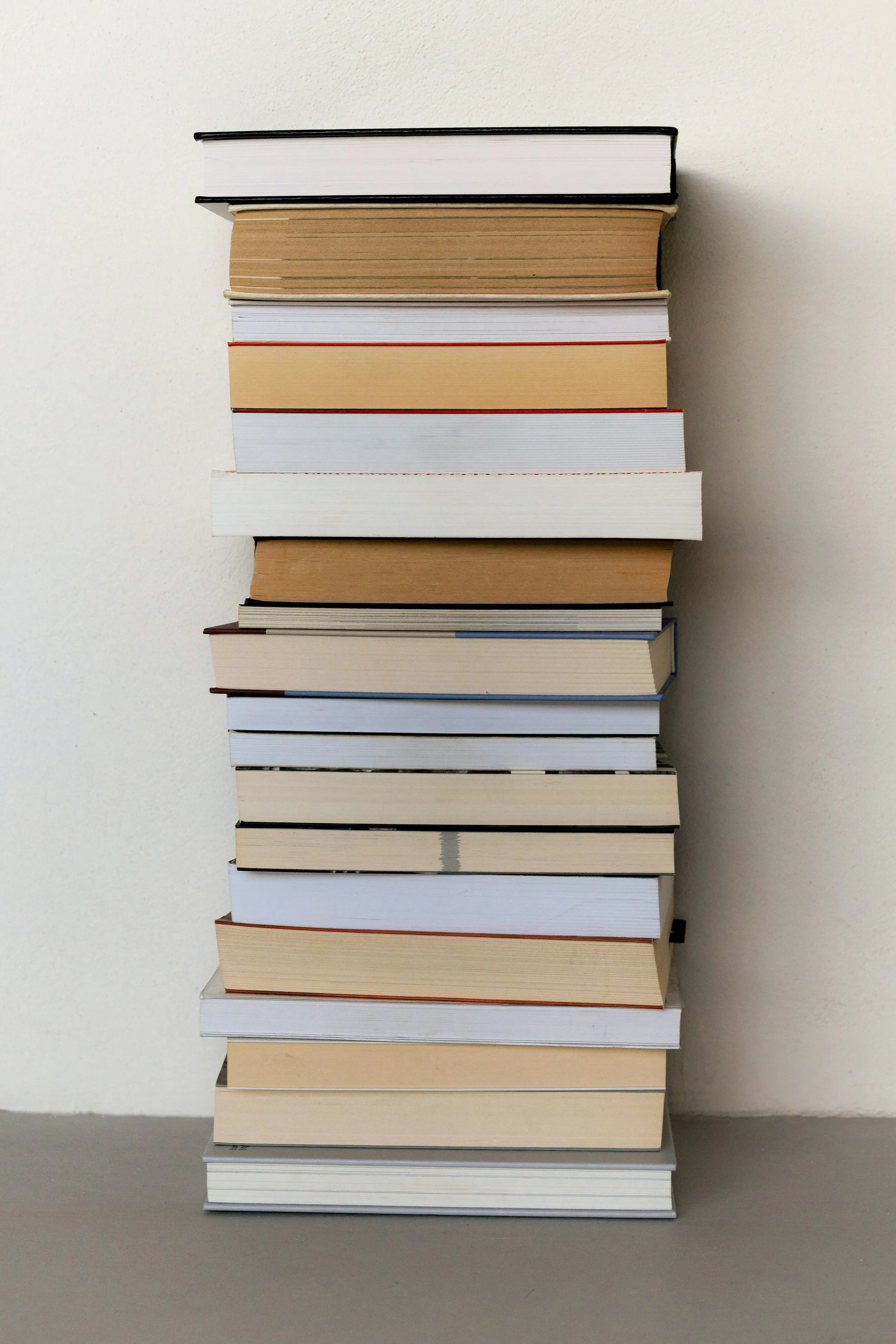 Pila di libri cartacei ordinati su sfondo bianco, simbolo delle pubblicazioni ed articoli scritti dalla consulente