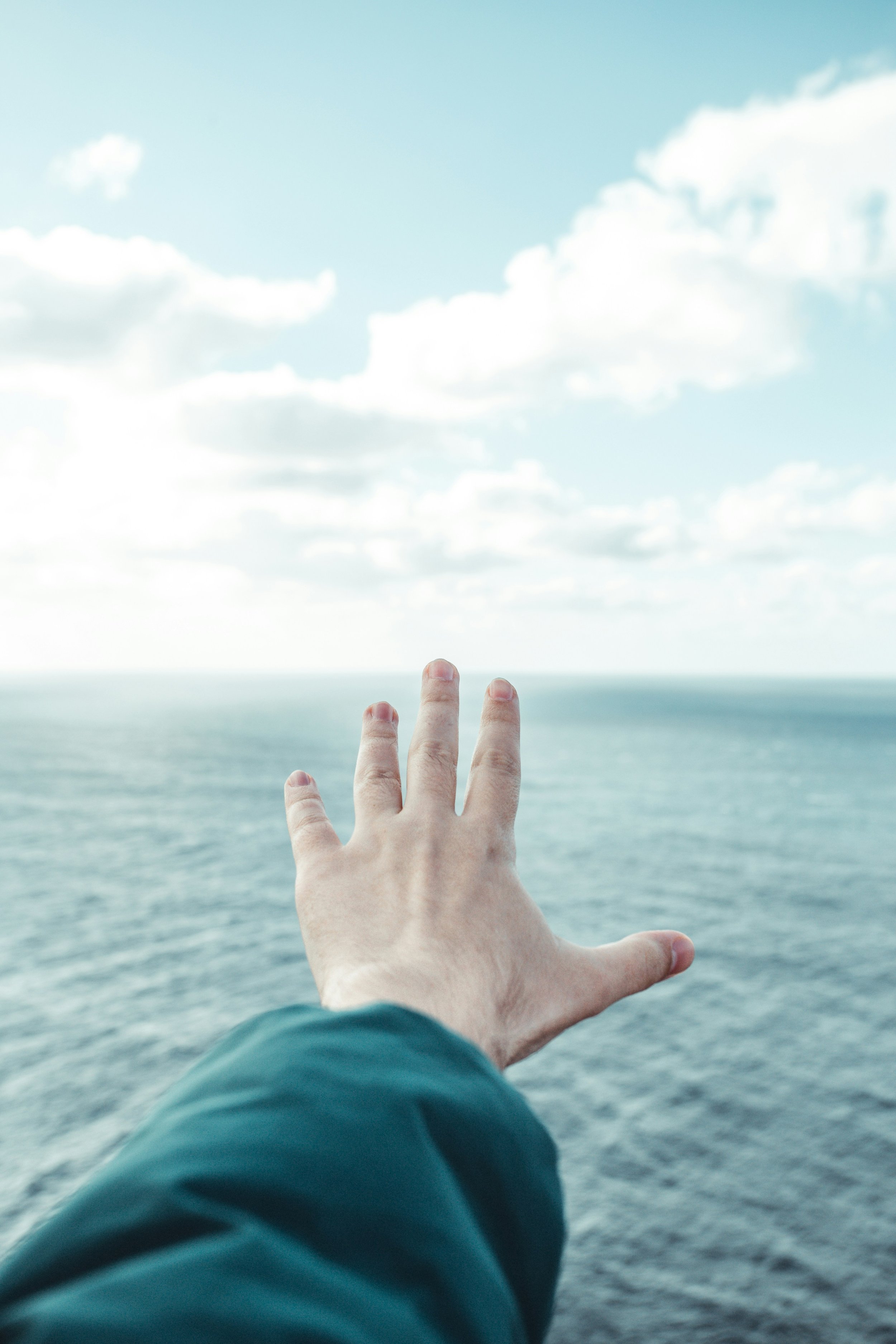 Mano tesa verso l'orizzonte del mare aperto, simbolo della visione a lungo termine e degli obiettivi di una consulenza strategica di marketing