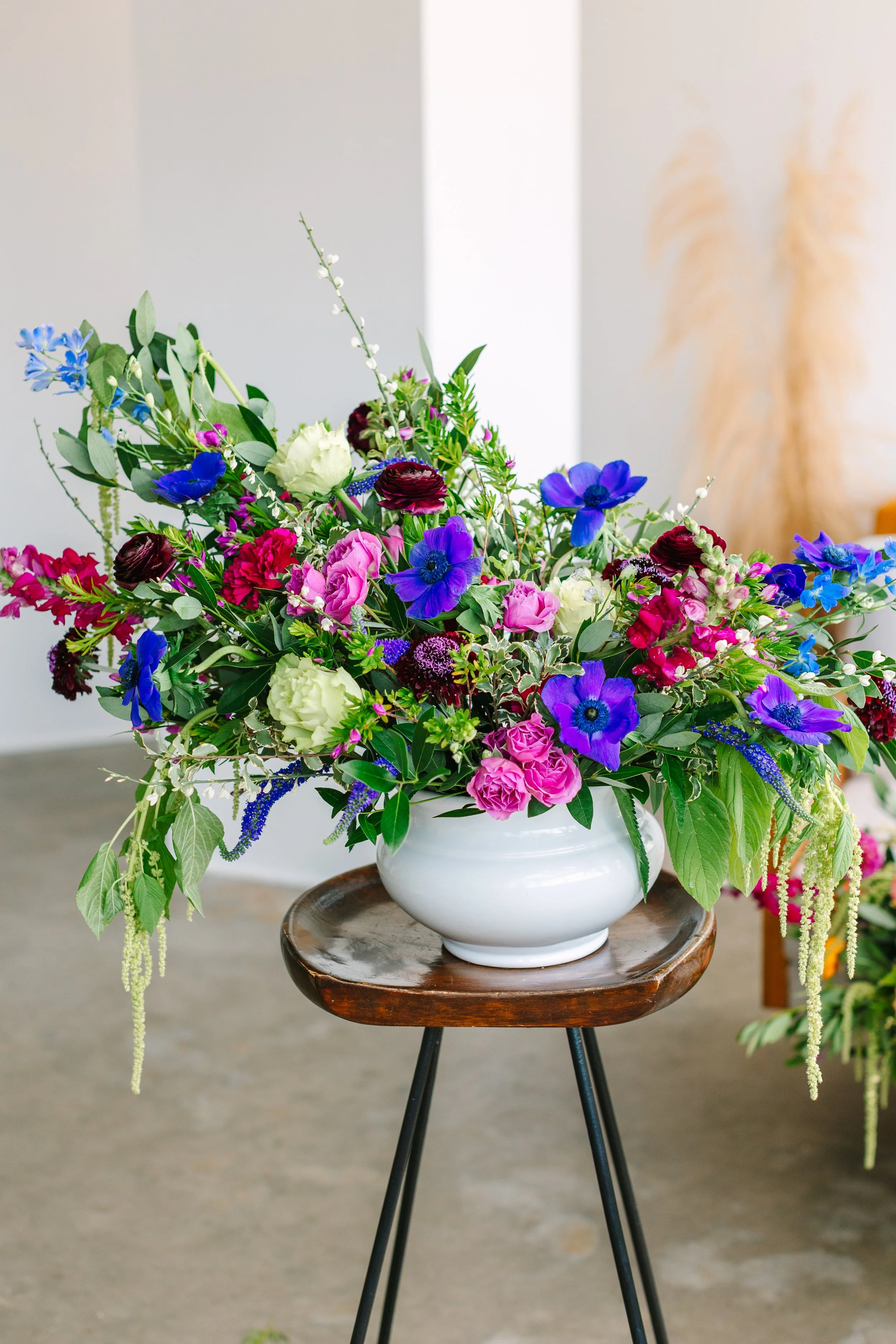 Colorful flower arrangement in a white vase on a small wooden table.