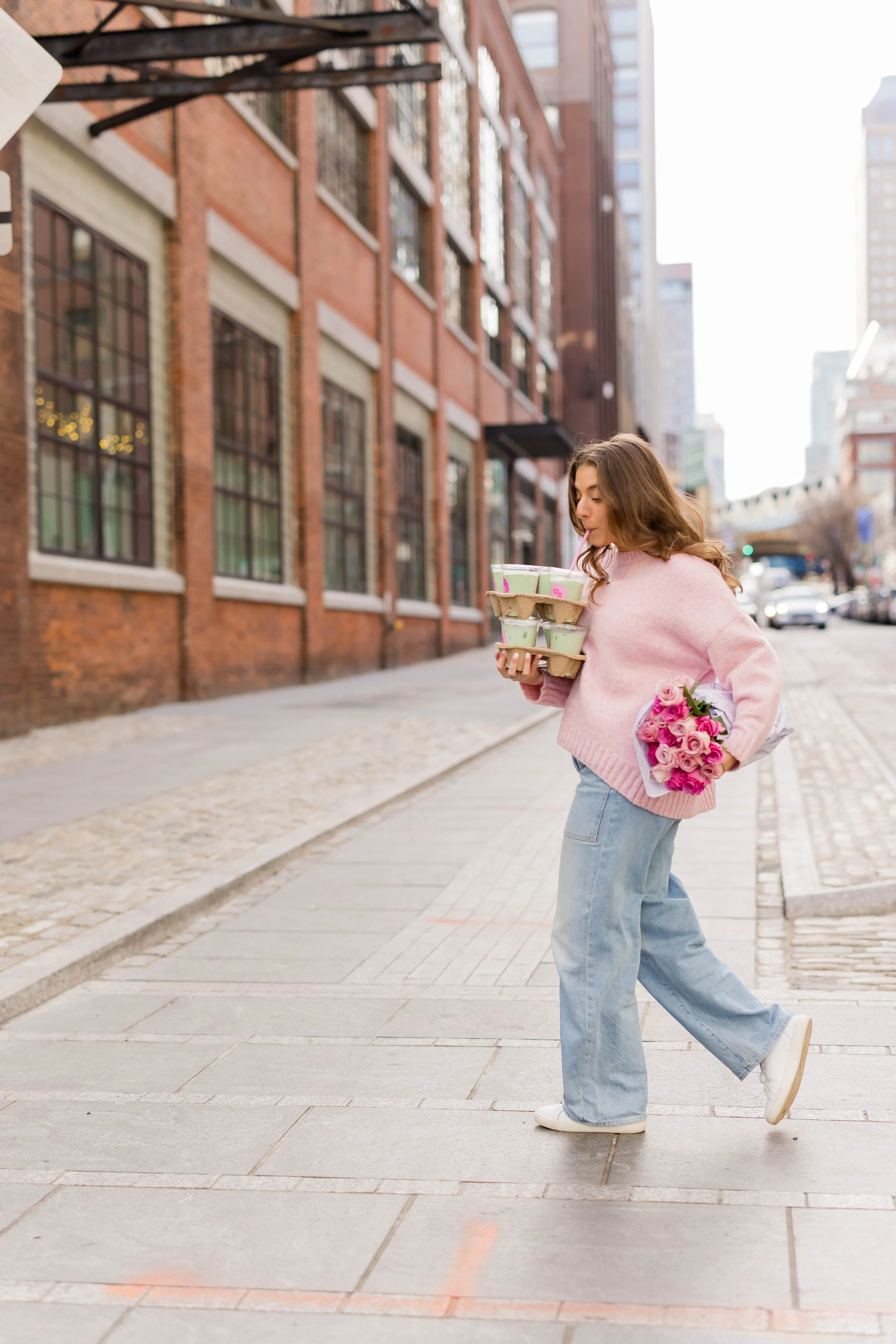 NYC Instagram coach carrying coffee and flowers on city street, embodying the balanced lifestyle of content creators