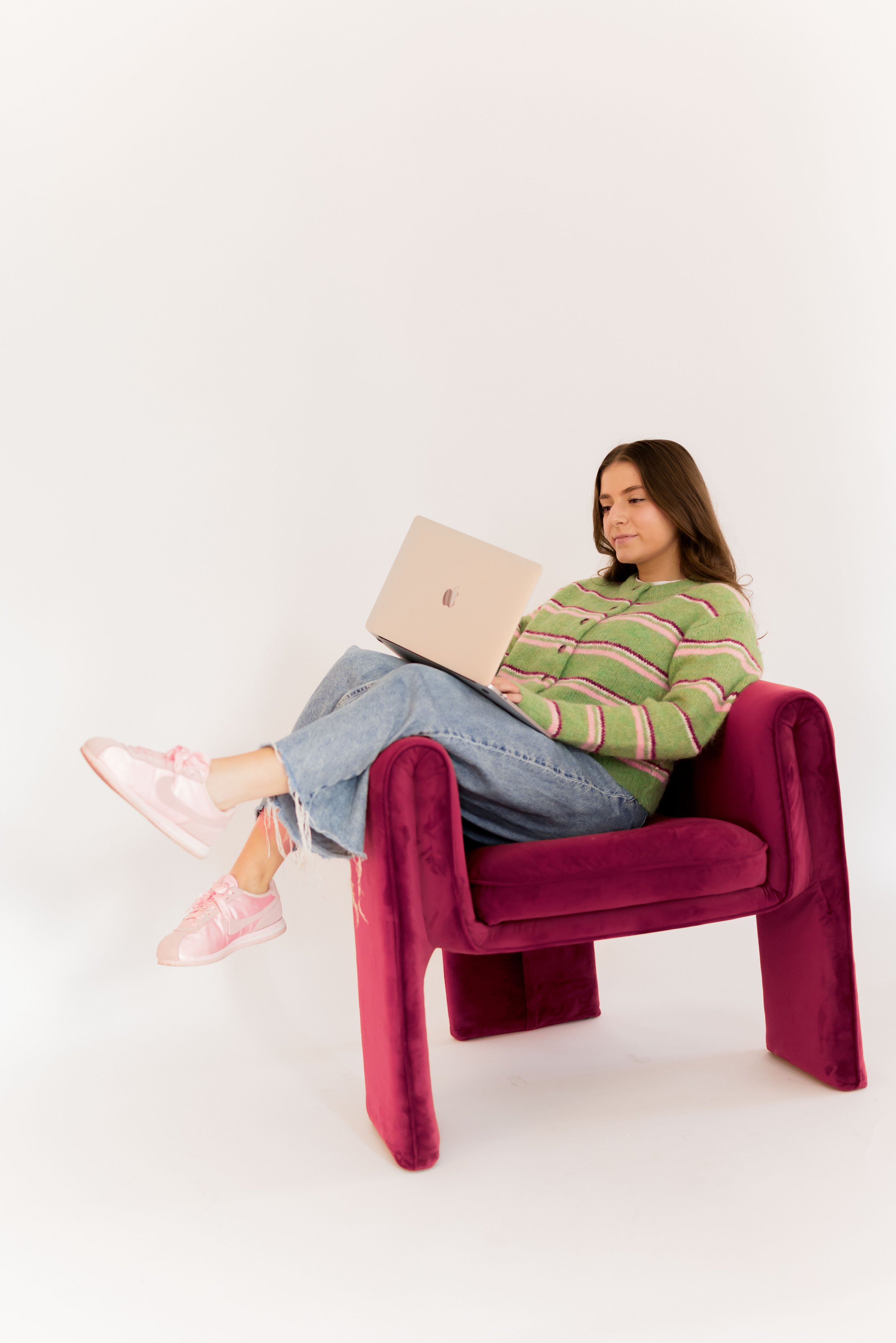 Instagram coach working on laptop in pink chair, creating content for Daily Content Club community members