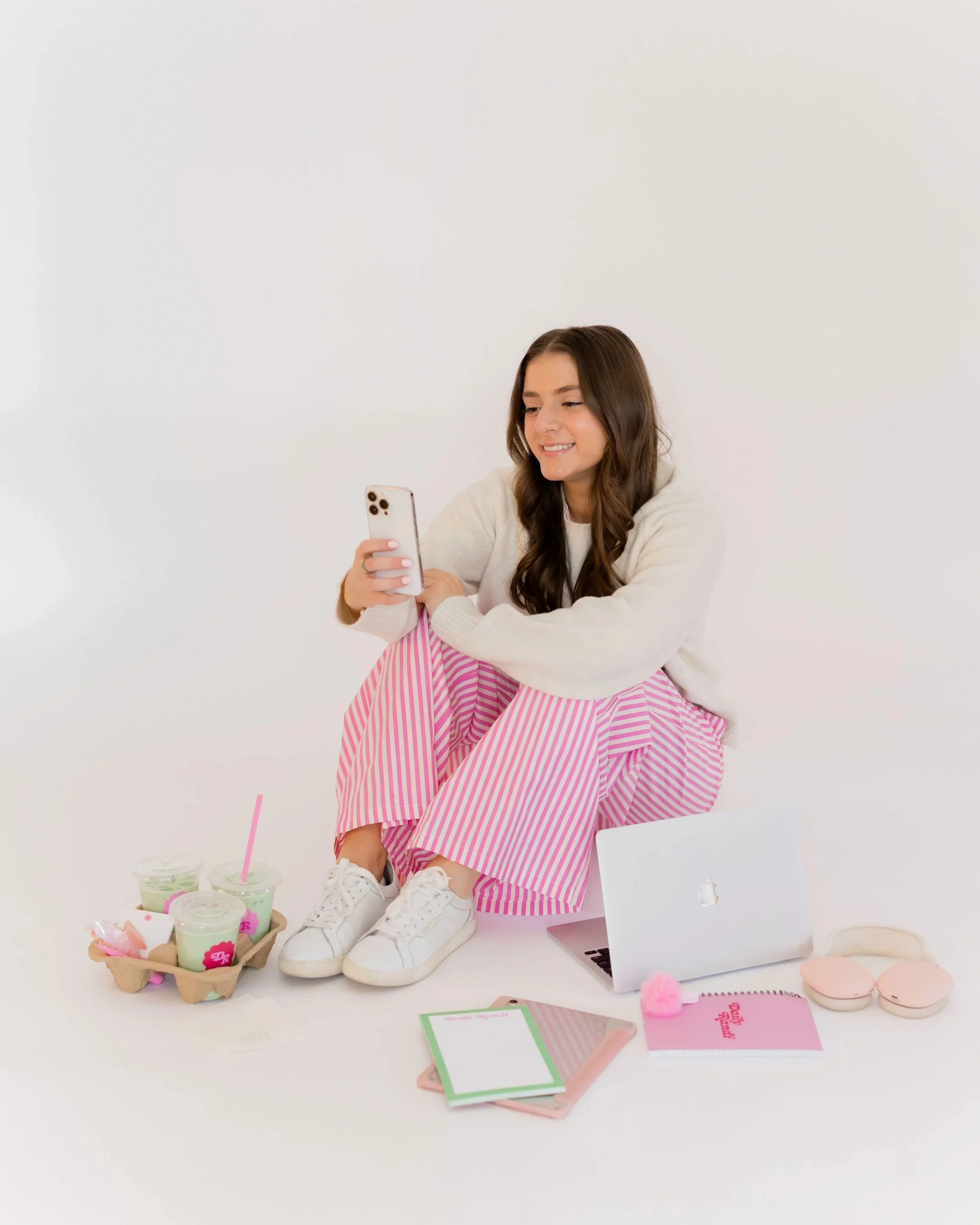 Instagram coach reviewing content strategy with phone and laptop surrounded by branded materials