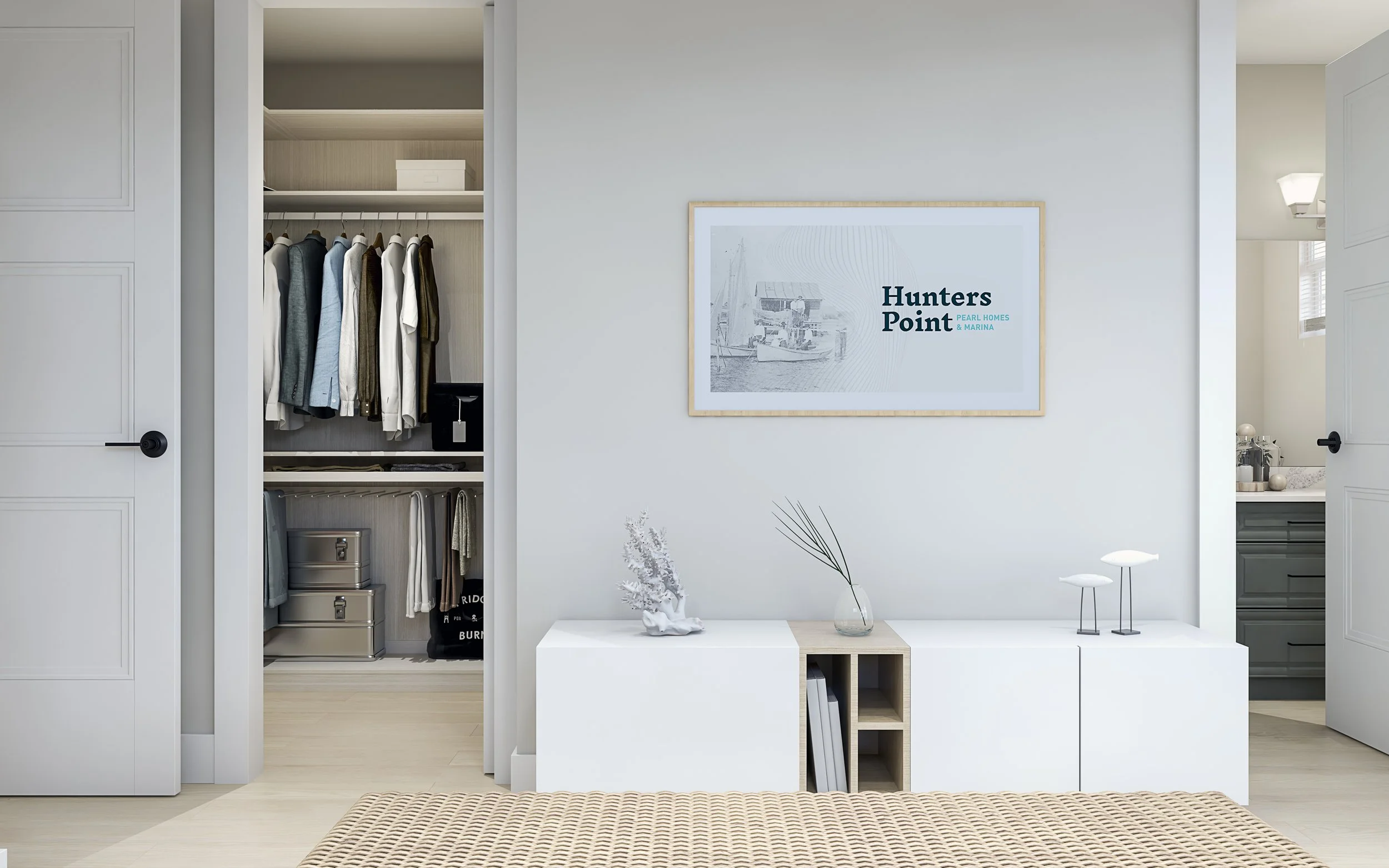 Modern bedroom with open closet containing hanging clothes and storage boxes, white walls, a picture of a harbor on the wall, minimalistic furniture with decorative items, and a view into the bathroom.