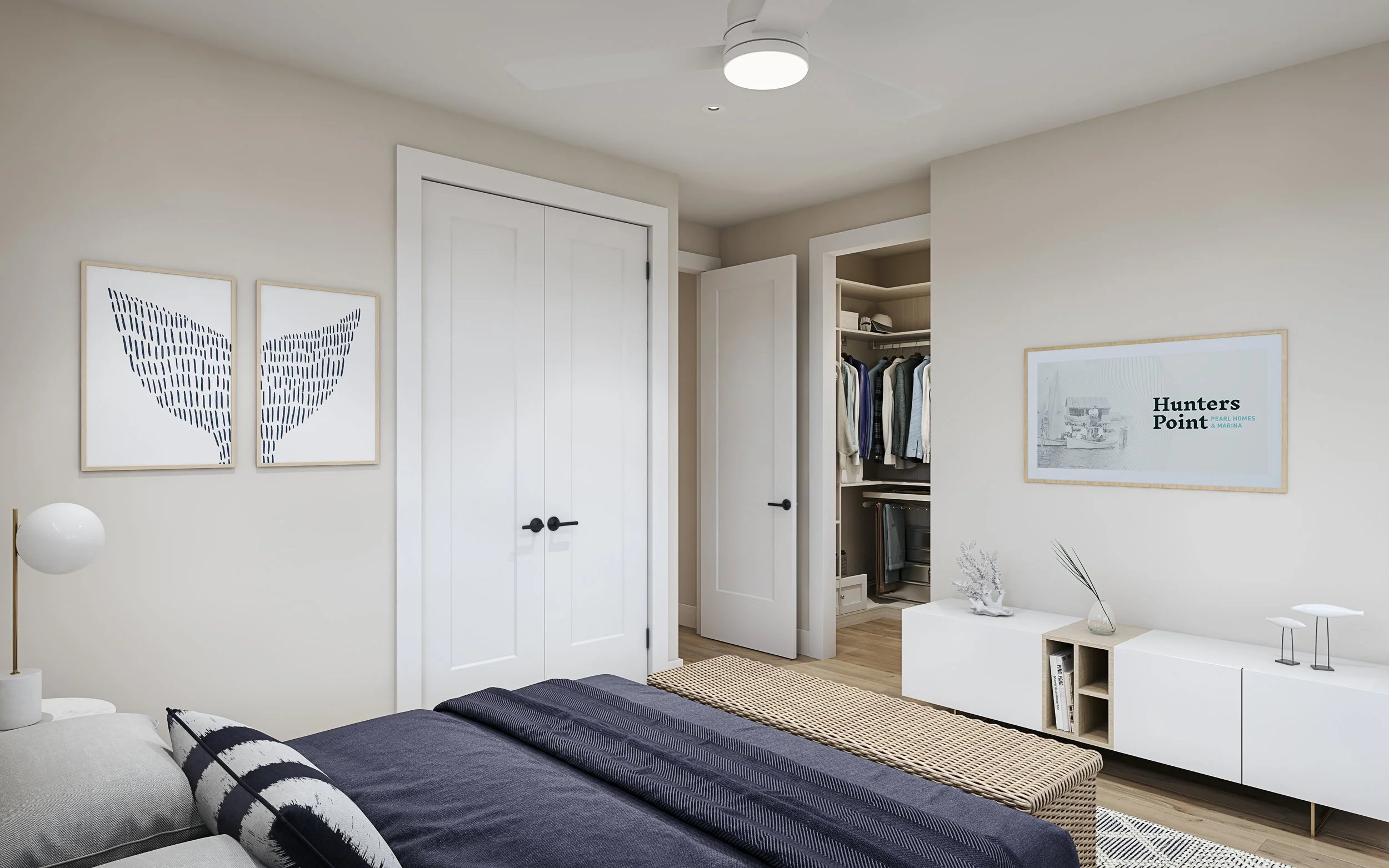 A bedroom with white walls, a bed with dark bedding and a patterned pillow, a white bedside table with a spherical lamp, and a white storage unit with decorative items and a framed picture on the wall. The open closet reveals hanging clothes.