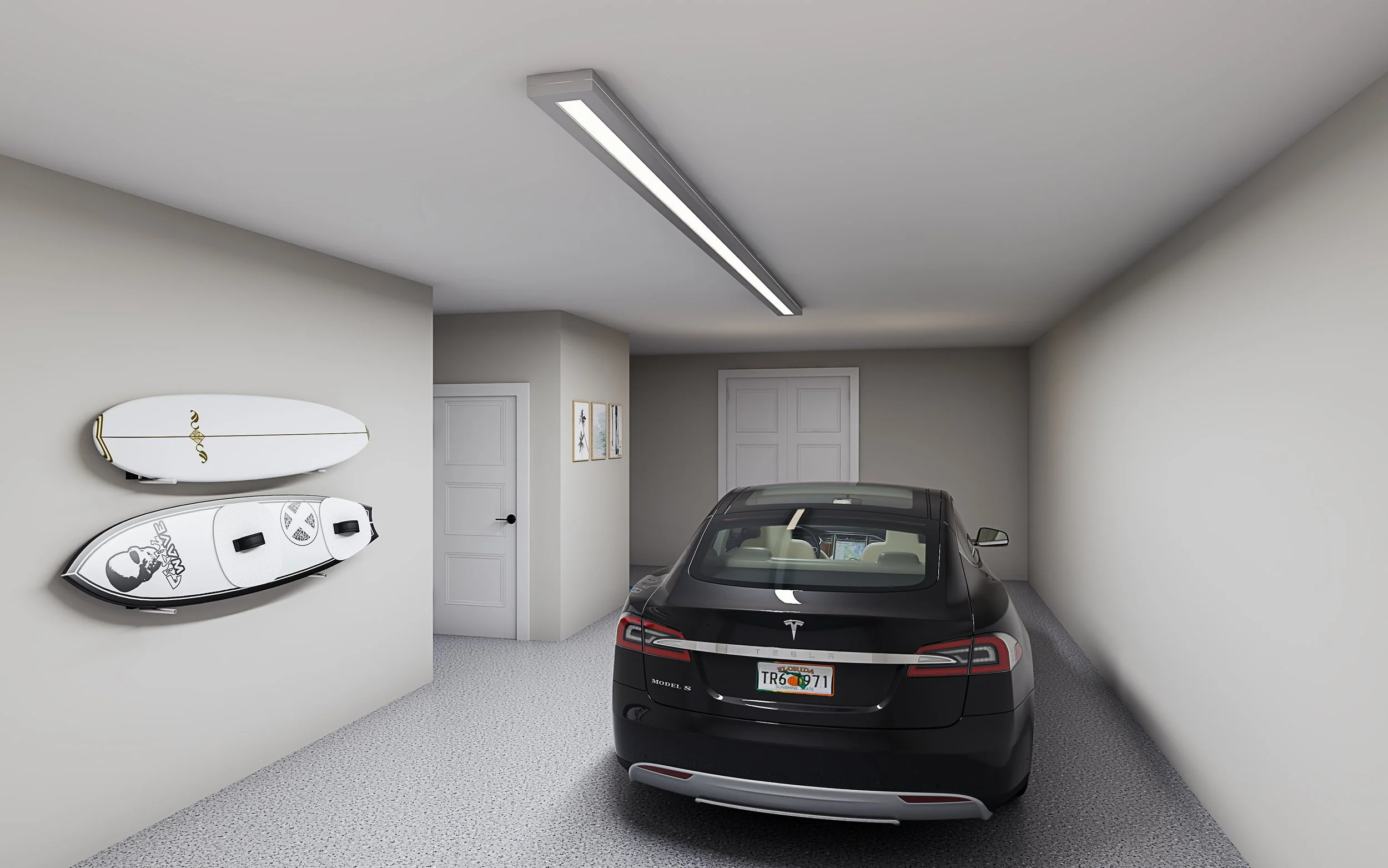 A garage with a black Tesla Model S parked inside. Two surfboards are mounted on the wall to the left, and three framed pictures are on the wall near the door. The garage has a white ceiling with a fluorescent light fixture.