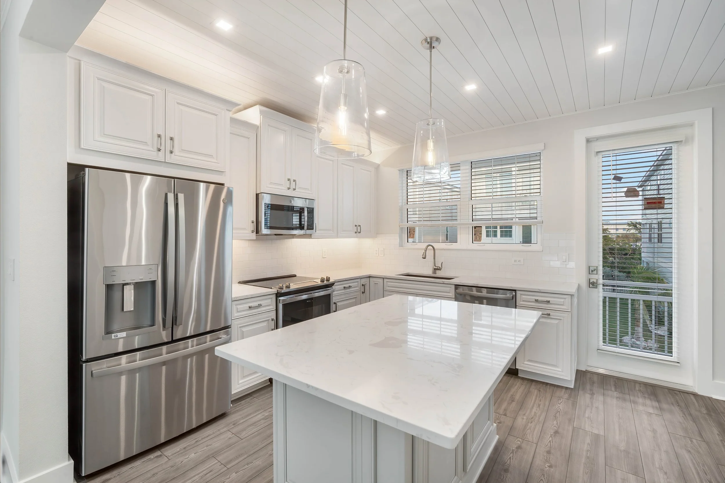 Modern white kitchen with stainless steel appliances and a large kitchen island.