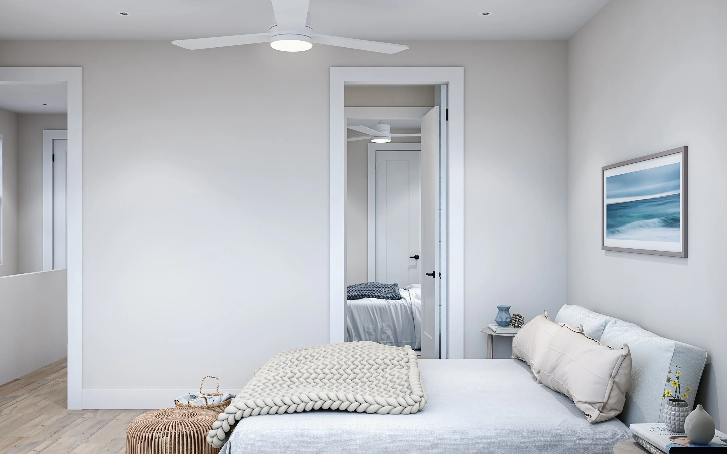 A bedroom with white walls, a bed with beige pillows and a chunky knit blanket, a small side table with vases and a book, and a framed ocean picture on the wall. A door leads to another room with a bed.