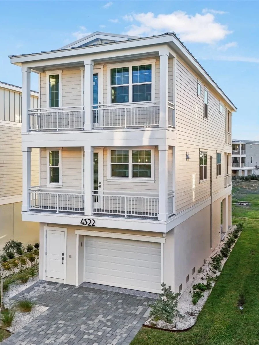 Three-story modern house with balconies, white siding, and a garage