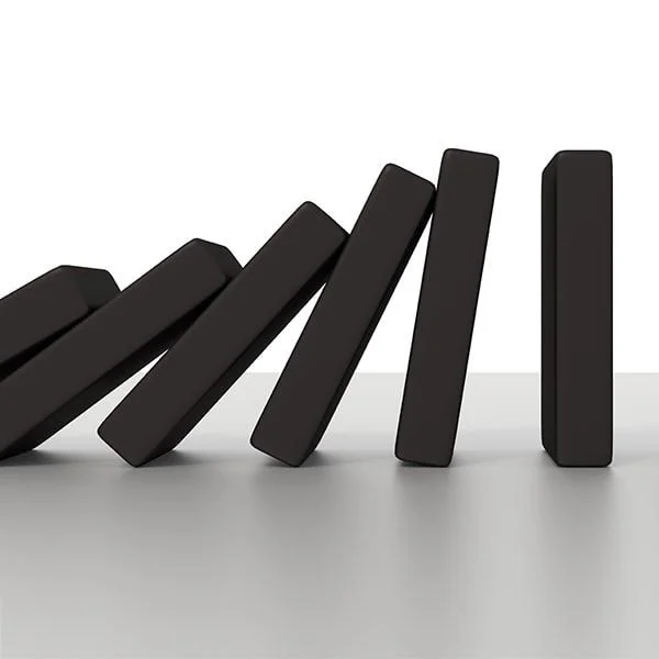 Black dominoes falling in sequence on a flat surface.