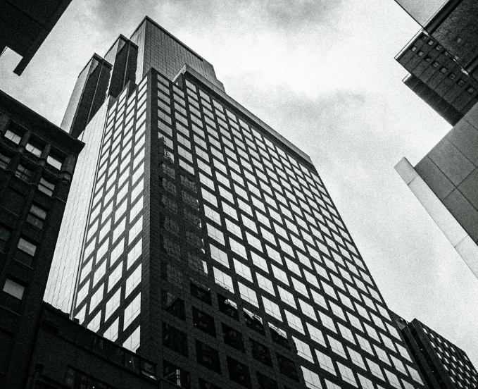 Looking up at tall modern skyscrapers in a city with cloudy sky.