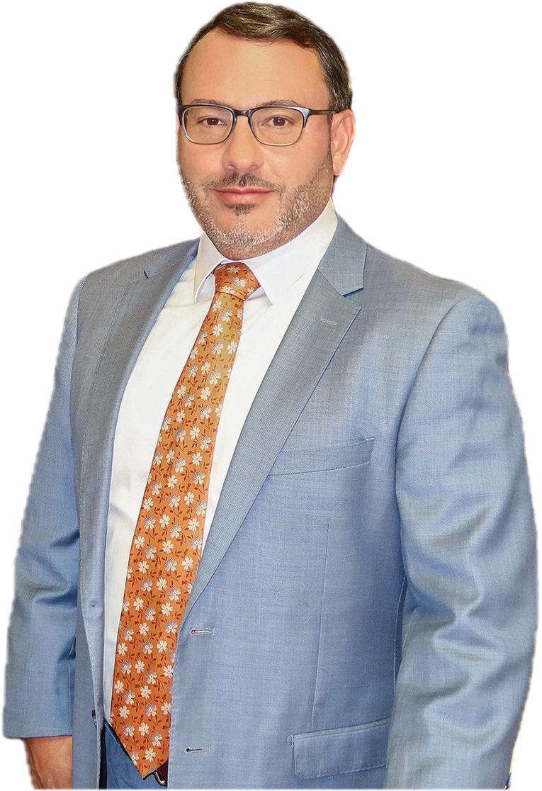 A man in a gray suit with a white shirt and an orange tie with white floral pattern posing for a photo.