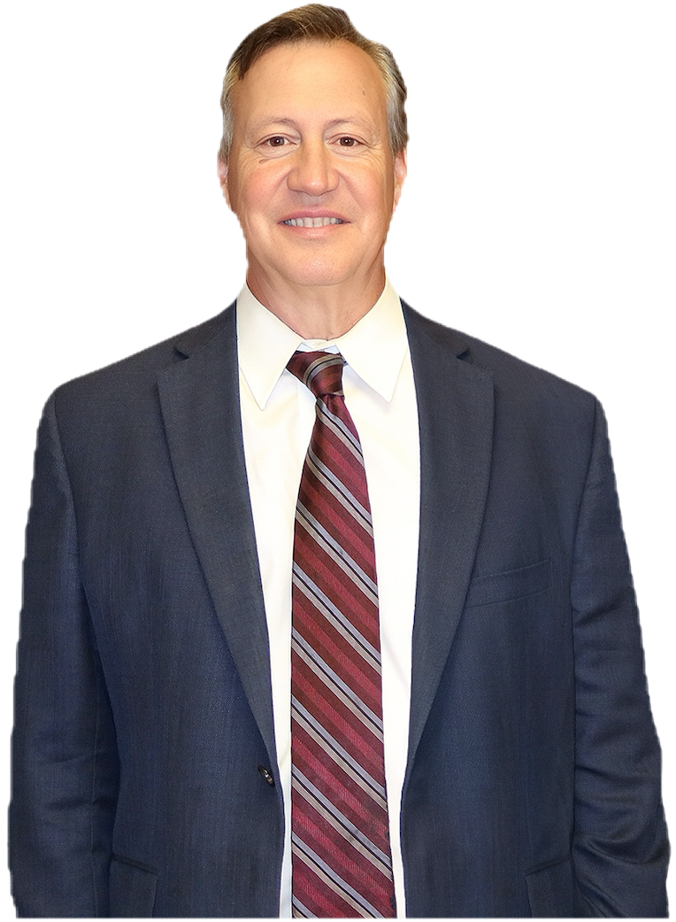 A middle-aged man wearing a dark suit, white shirt, and a maroon striped tie, standing and smiling