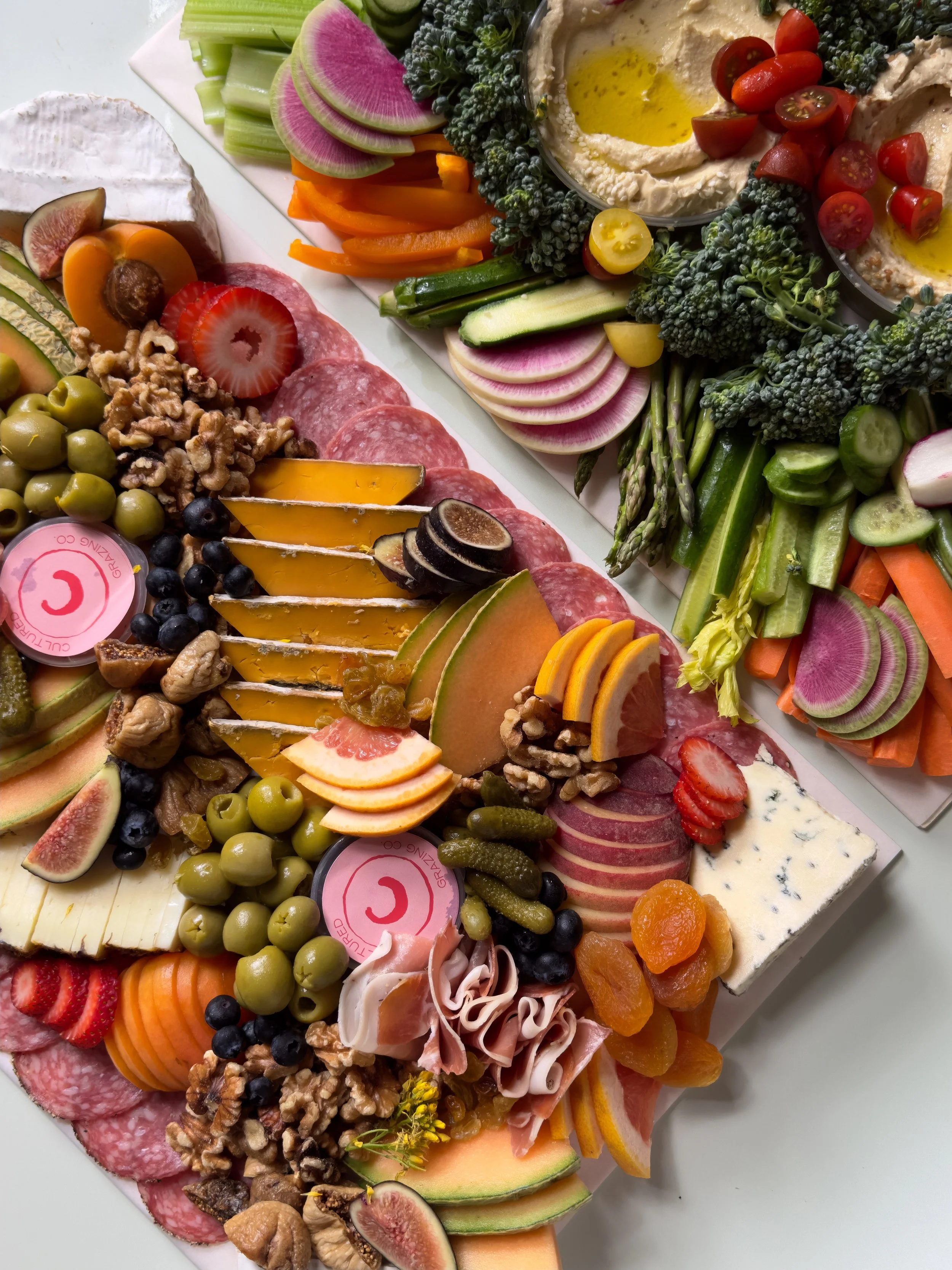 Colorful cheese and charcuterie board with fruits, vegetables, nuts, and dips.