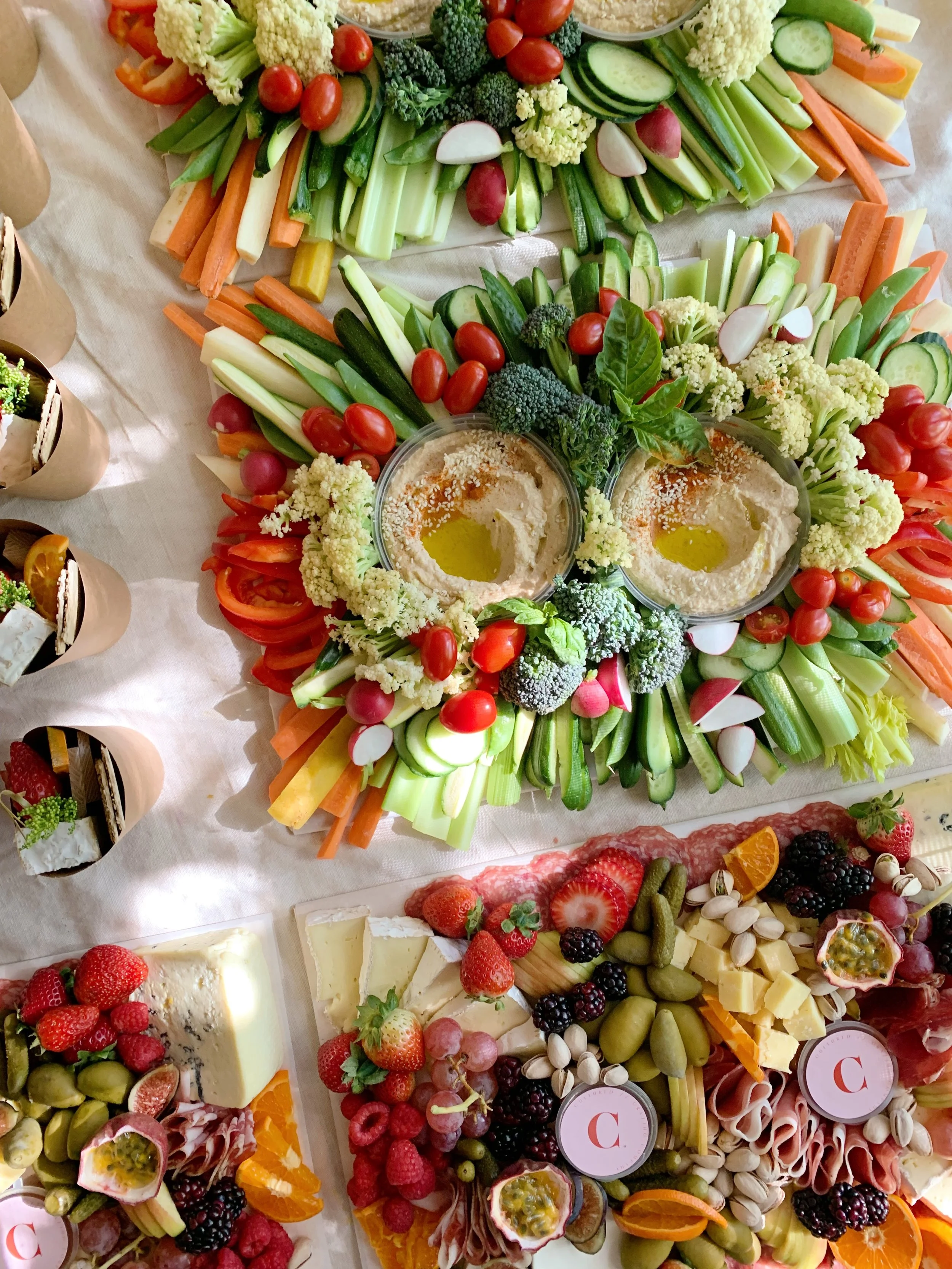 Colorful vegetable platter with cherry tomatoes, celery, carrots, broccoli, radishes, and hummus with olive oil