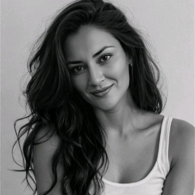 Black and white portrait of a young woman with long wavy hair, smiling gently at the camera, wearing a white tank top.