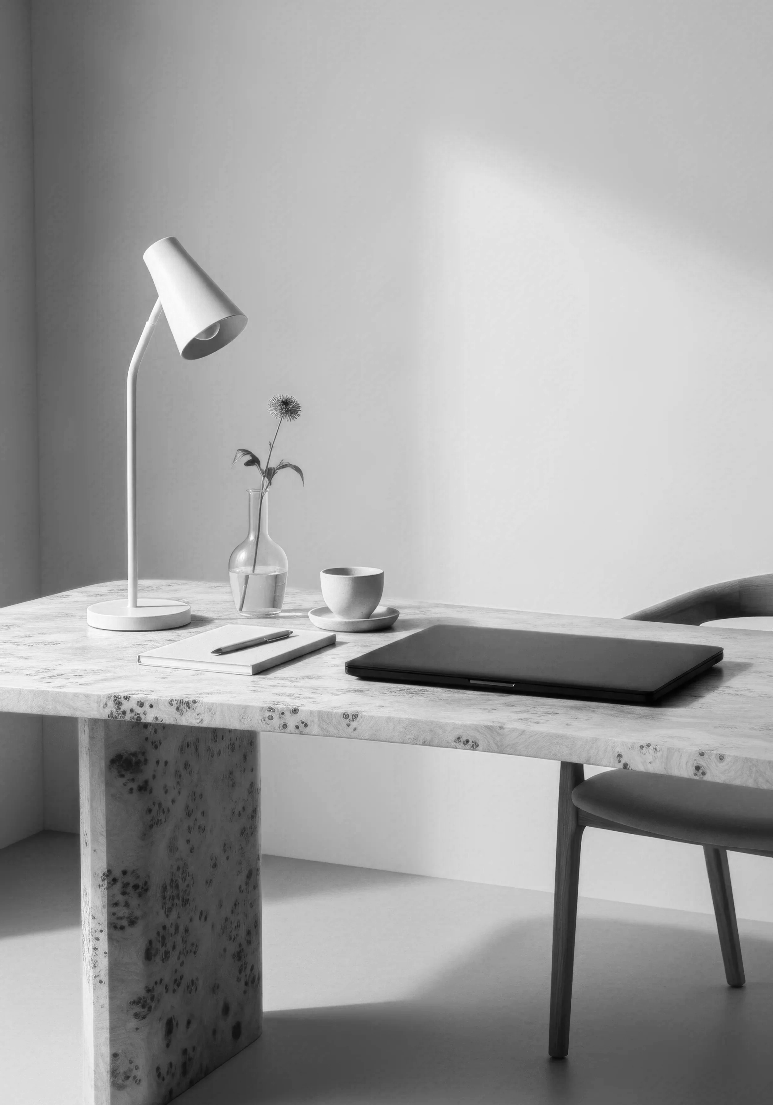 Minimal workspace with a desk lamp, notebook, pen, and closed laptop, representing focused learning and reflection.