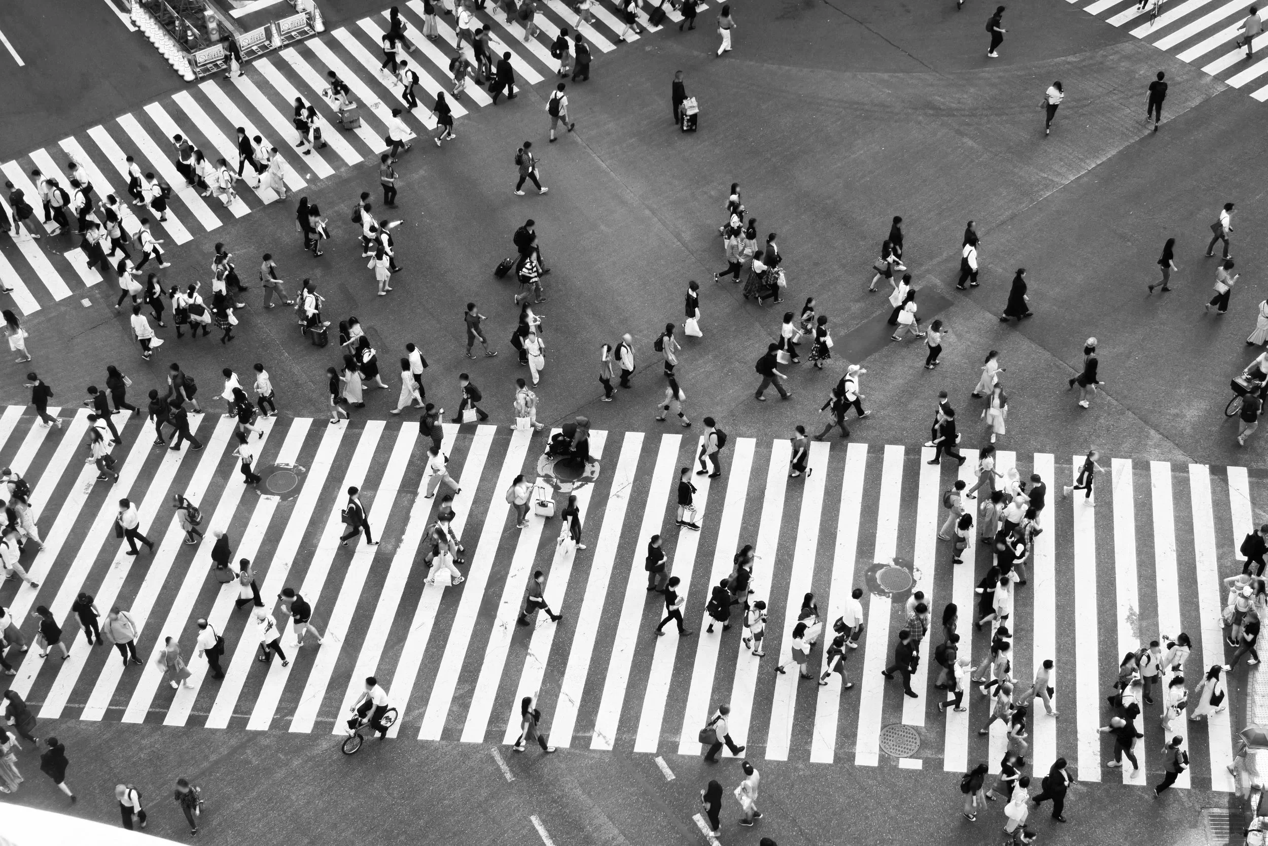 People crossing a city intersection from above, representing collective movement and large-scale collaboration.