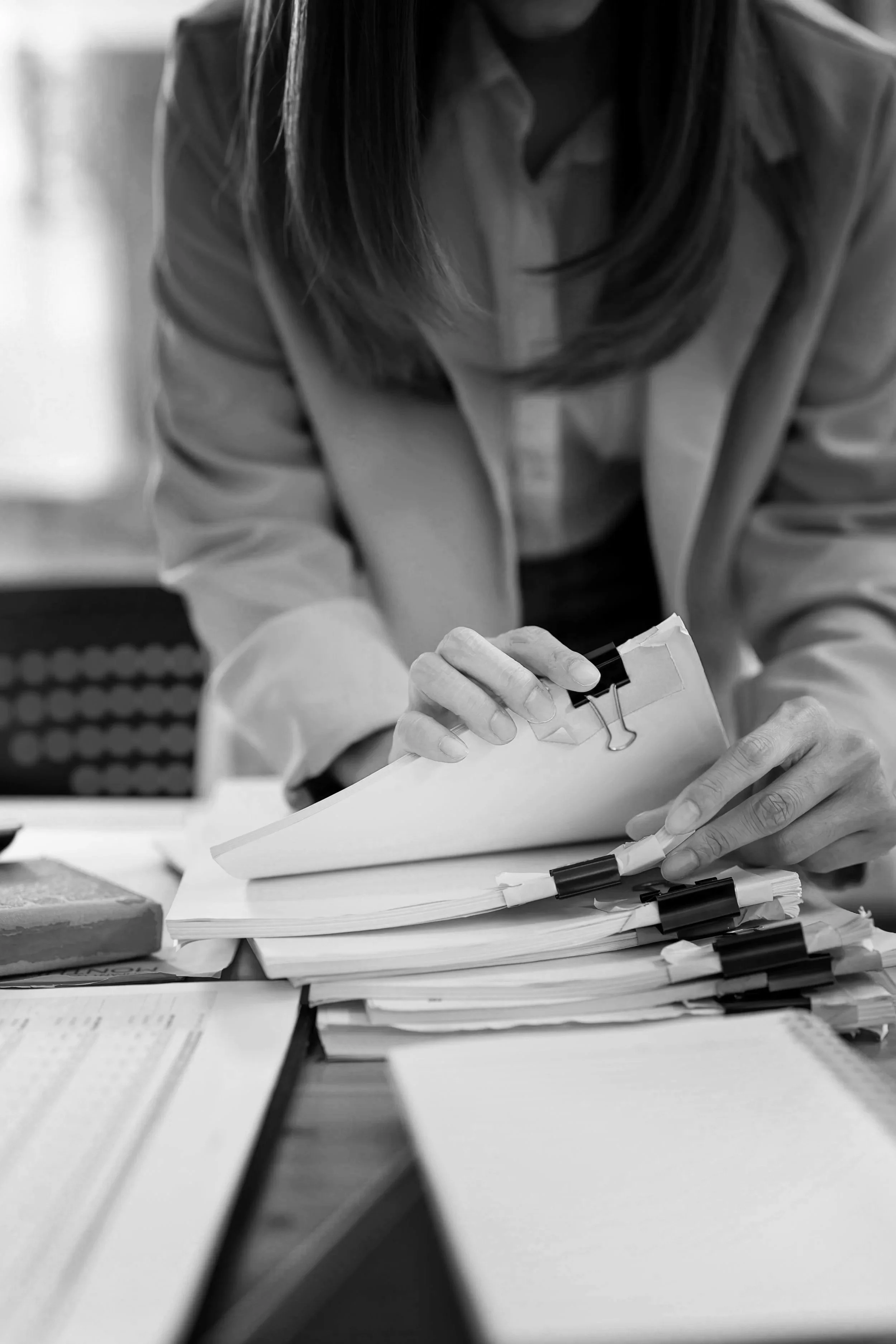 Person reviewing documents and taking notes at a desk, representing press searching.