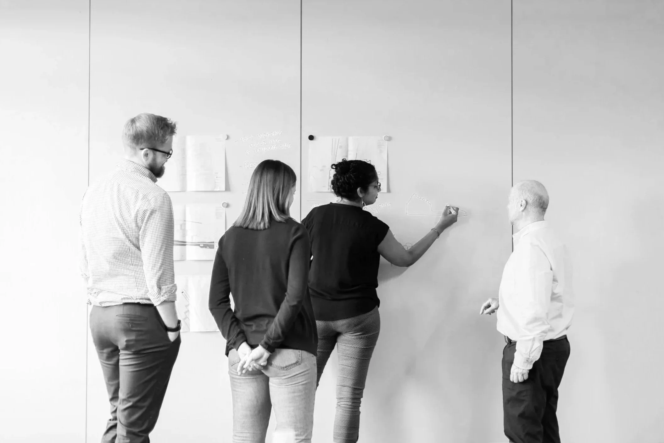 Group of professionals collaborating around a whiteboard during a research discussion.