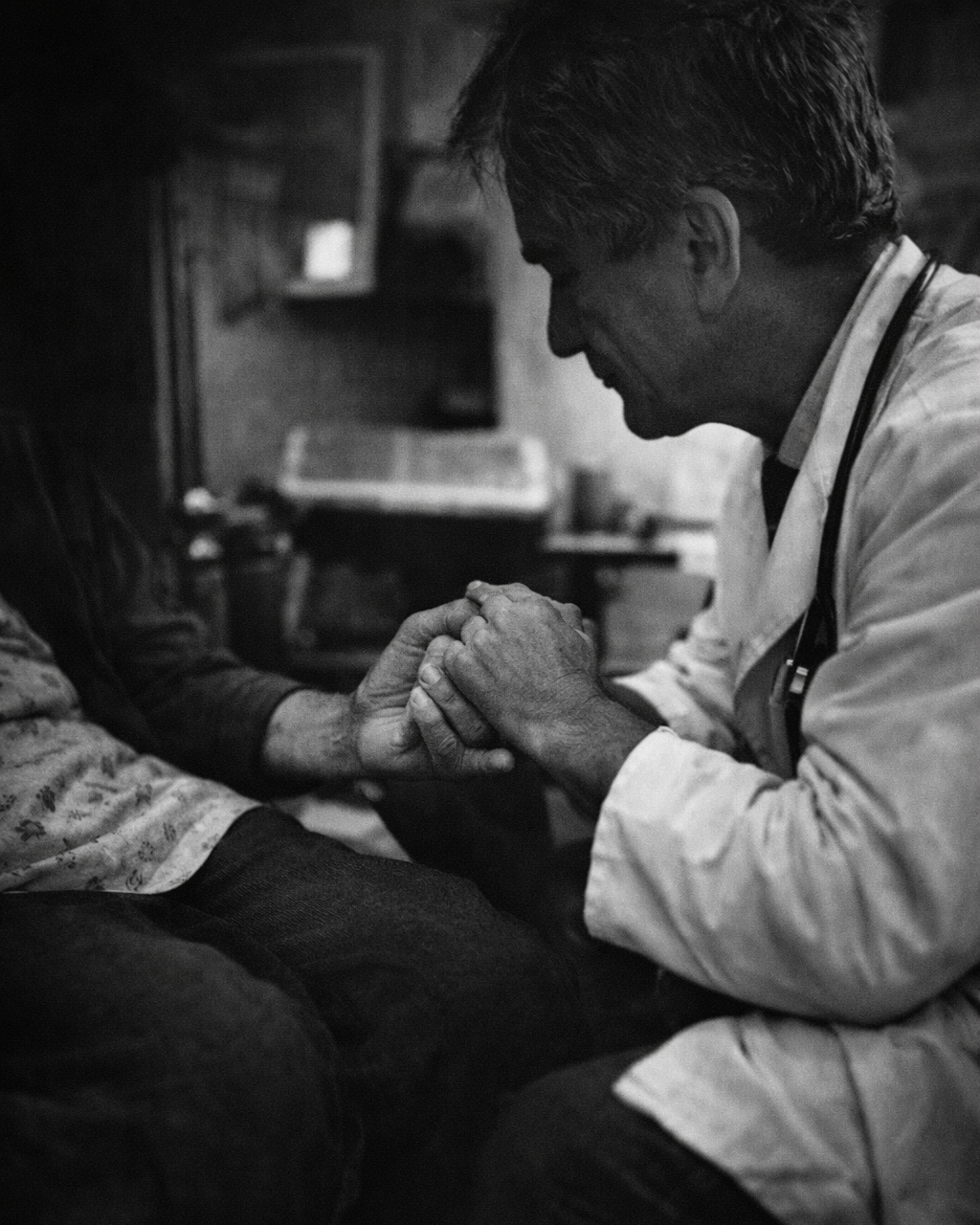Healthcare professional holding a patient’s hands during a clinical interaction, reflecting care focused on human outcomes.