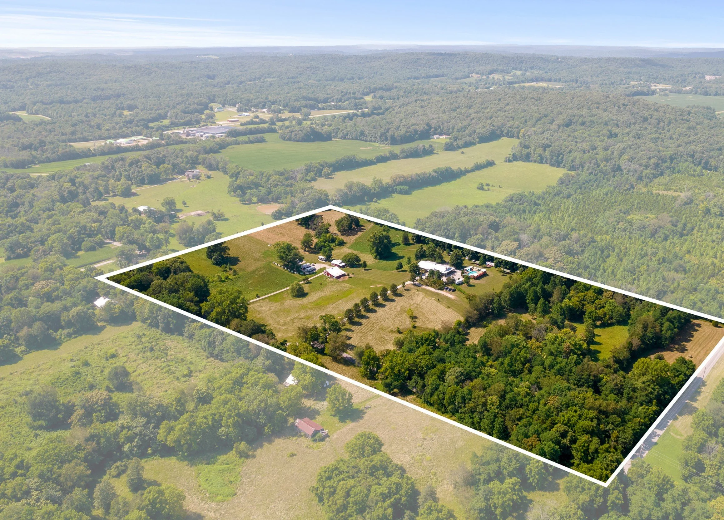 Aerial drone photo showing a large rural property with trees and open land, highlighted with a white boundary outline. High-resolution land overview imaging for real estate and acreage listings in Kentucky.
