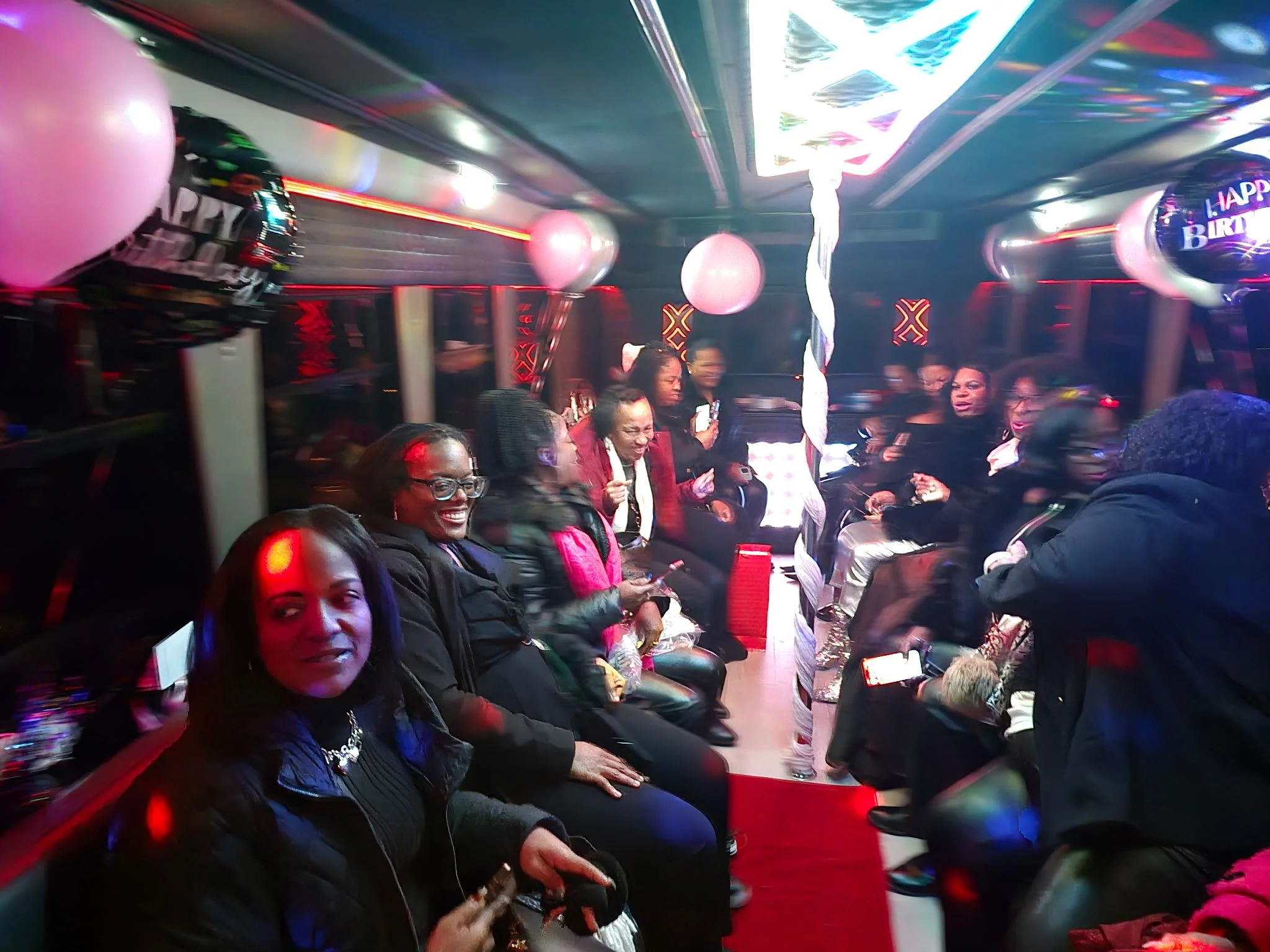 People celebrating a birthday at a party with pink balloons, a 