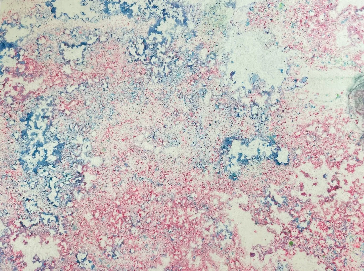 Close-up of a stained surface with splotches of blue, red, and beige colors.