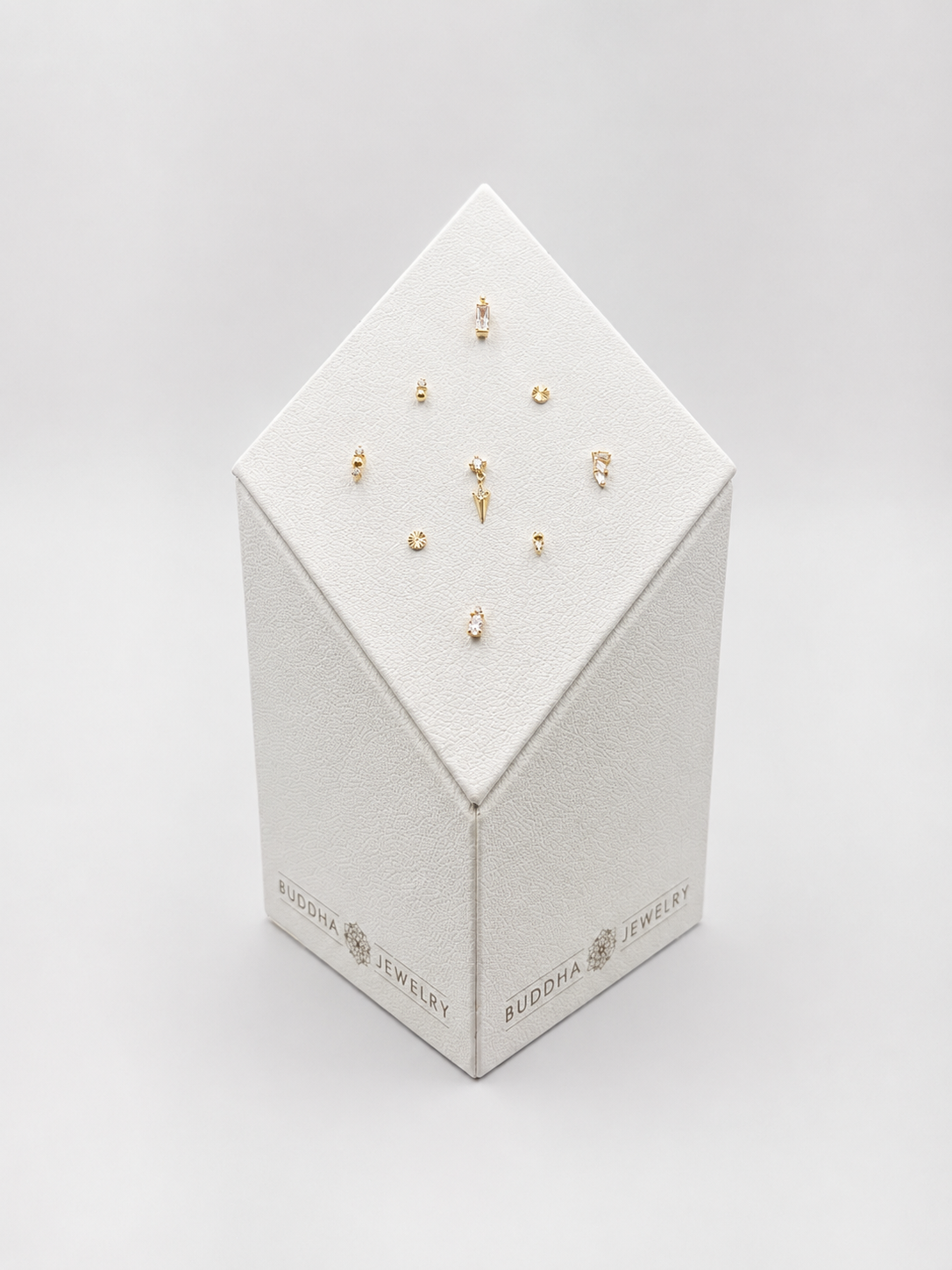 Boîte en forme de diamant avec des bijoux en or et diamants exposés dessus, étiquetée 'Buddha Jewelry'