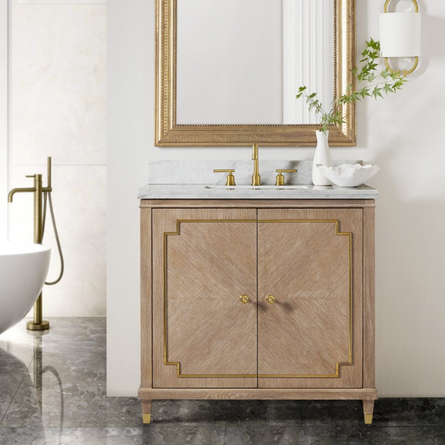 The Noelle vanity with a gold mirror frame, oak veneer, white Carrara marble top, and brass hardware accents by Modern History.