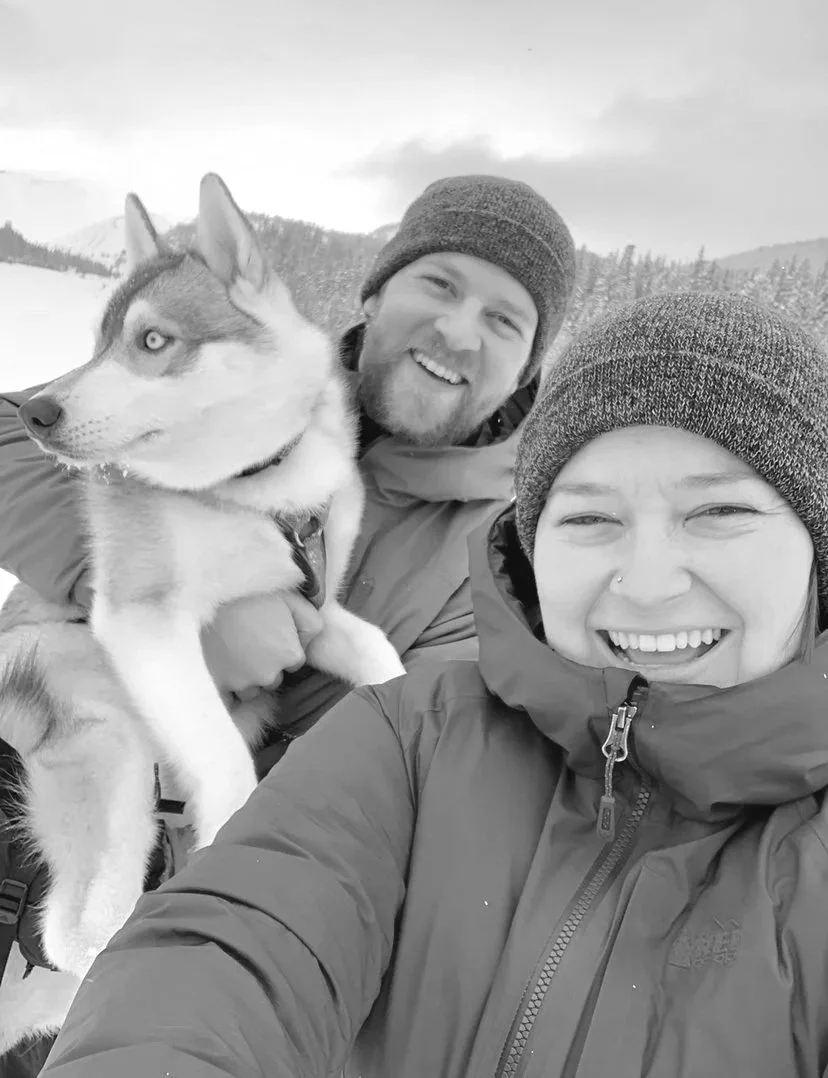 Two people in the snow with a dog