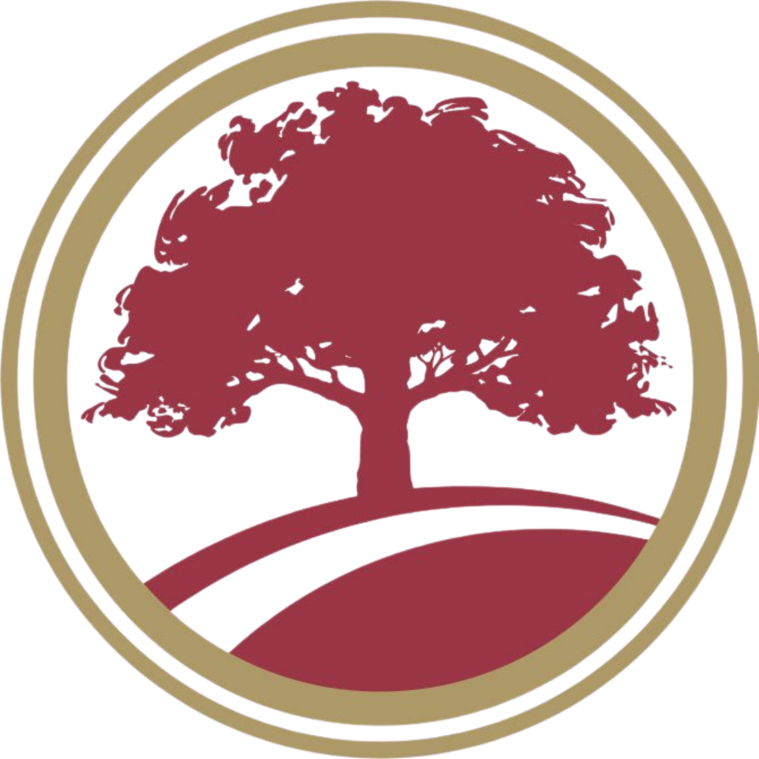 A circular emblem featuring a red tree with a broad canopy, set against a white background with a gold border.