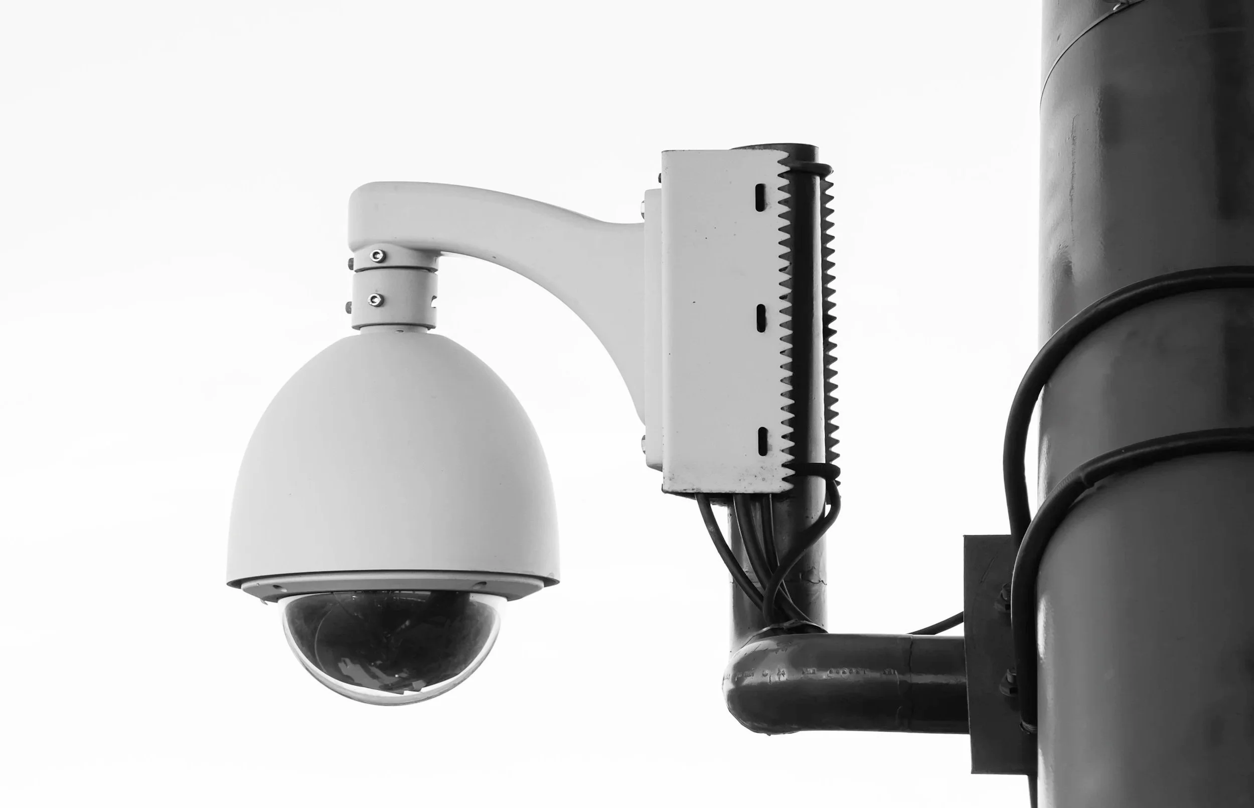 Security camera mounted on a pole with wires attached.