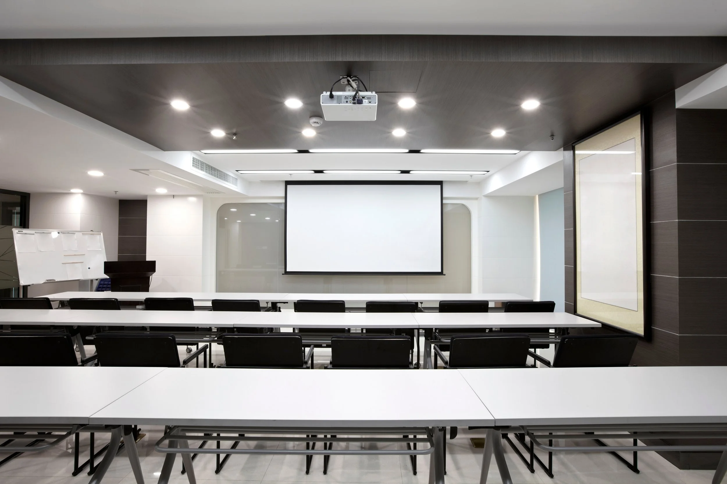 Modern conference room with ceiling-mounted projector and presentation screen