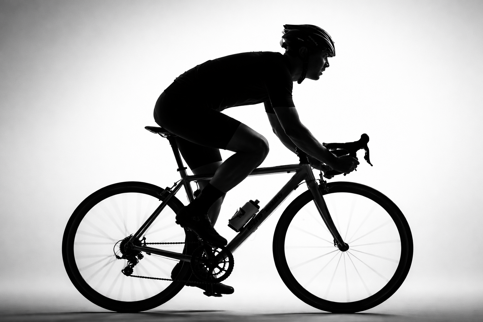 Silhouette of a person riding a bicycle wearing a helmet, against a plain background.
