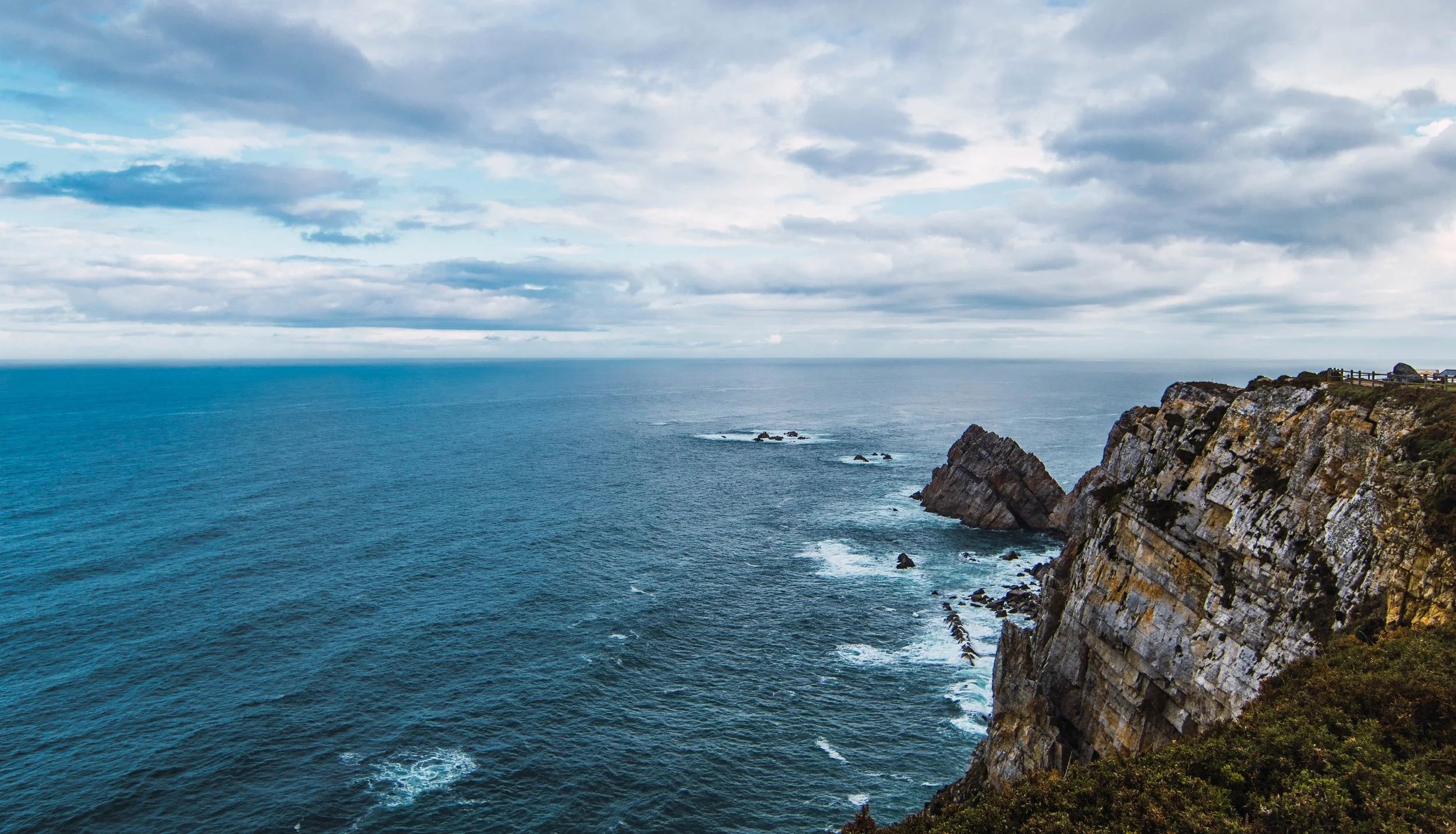 high-angle-shot-sea-near-mountain-cloudy-sky-cabo-penas-asturias-spain.jpg