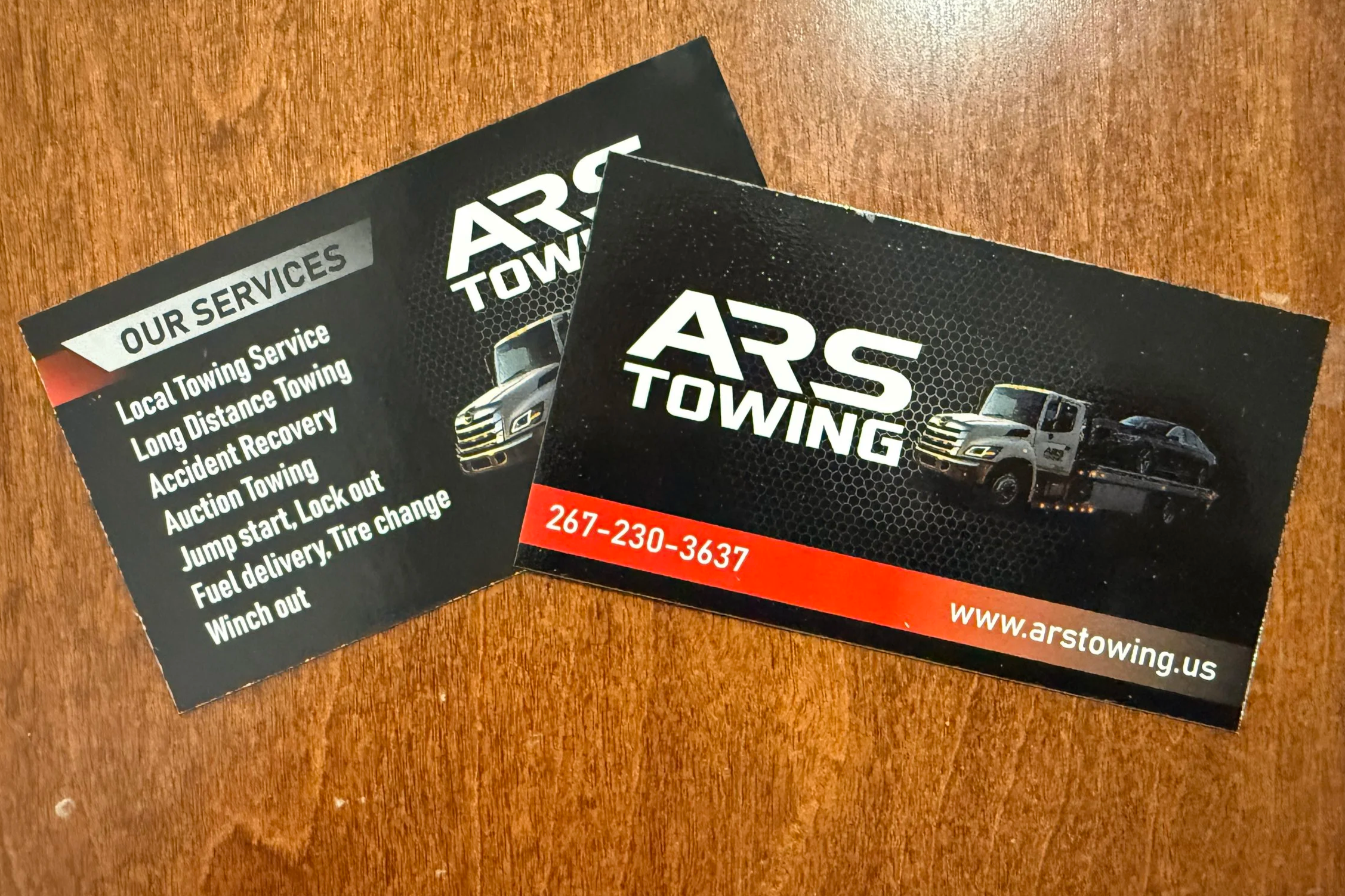 ARS Towing custom business cards featuring red and white text on a black background next to a black tow truck.