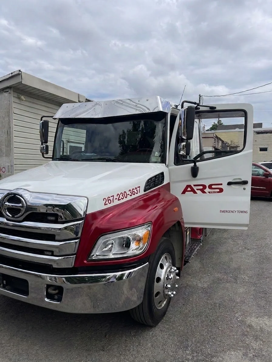ARS Towing commercial Hino flatbed rollback tow truck providing roadside assistance and vehicle transport