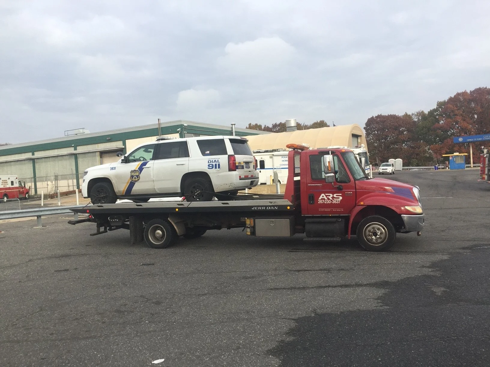 A red tow truck transporting a white police SUV with a 